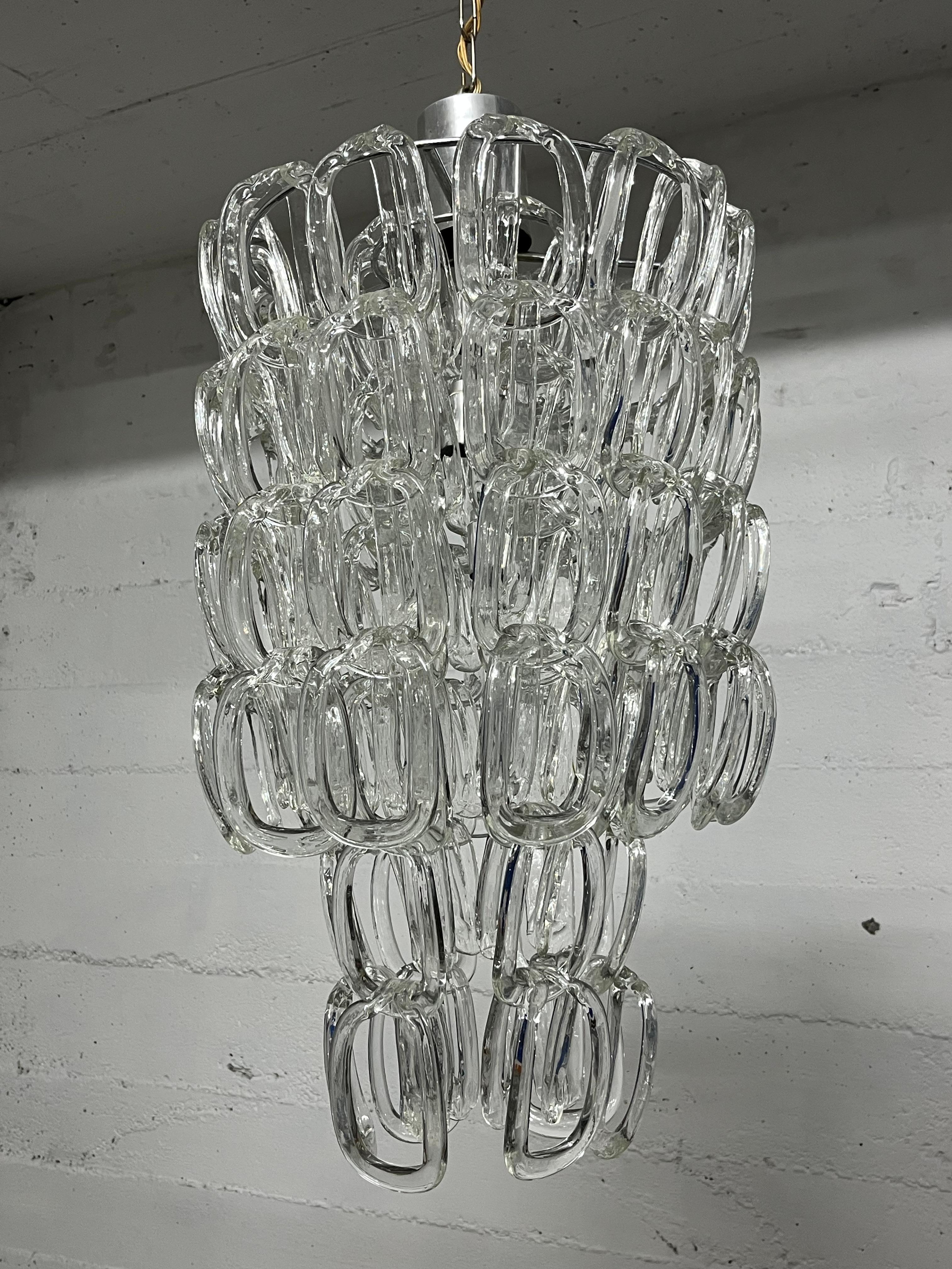 Lampadario in vetro di Murano di metà secolo attribuito ad Angelo Mangiarotti per Vistosi, anni '60
5 luci, lampade E14 e E27.
Struttura in metallo, vetro intatto.
Buone condizioni.
Altezza compresa la catena 110 cm, altezza del solo lampadario 70