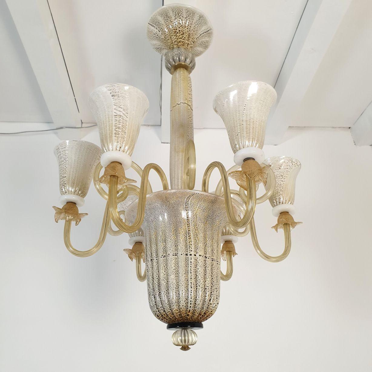 Araña alta de cristal de Murano de mediados de siglo, atribuida a Venini, Italia Años 60.
La araña es de cristal de Murano moteado en blanco y marrón, con adornos de pan de oro.
La araña de Murano de estilo neoclásico tiene 6 brazos y luces.
El