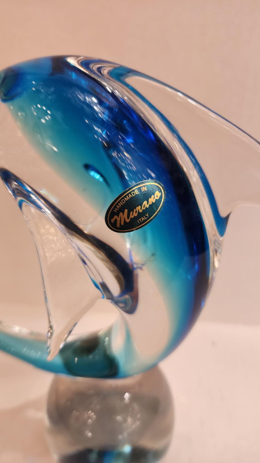Questo articolo presenta un delfino in vetro di Murano seduto sopra una sfera di vetro trasparente. Sebbene la scultura sia per lo più trasparente, il bellissimo vetro blu sulla schiena del delfino aggiunge una dimensione sufficiente a questo