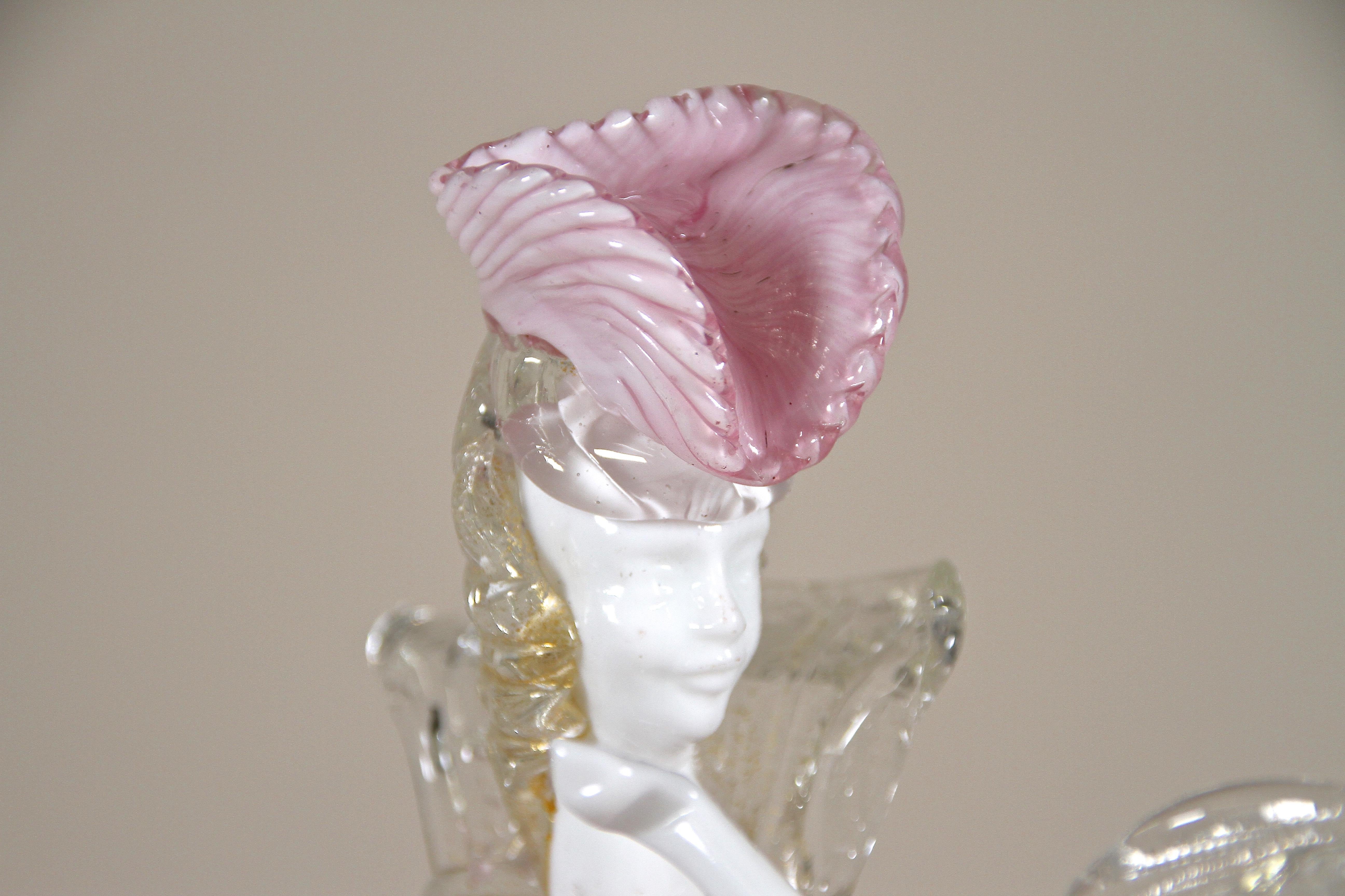 Artfully designed Murano glass figurine out of the famous workshops in Venice from the 1950s. Standing on a golden round base this absolutely fantastic made murano sculpture depicts a beautiful venetian lady dancing in a noble pink/ white robe. The