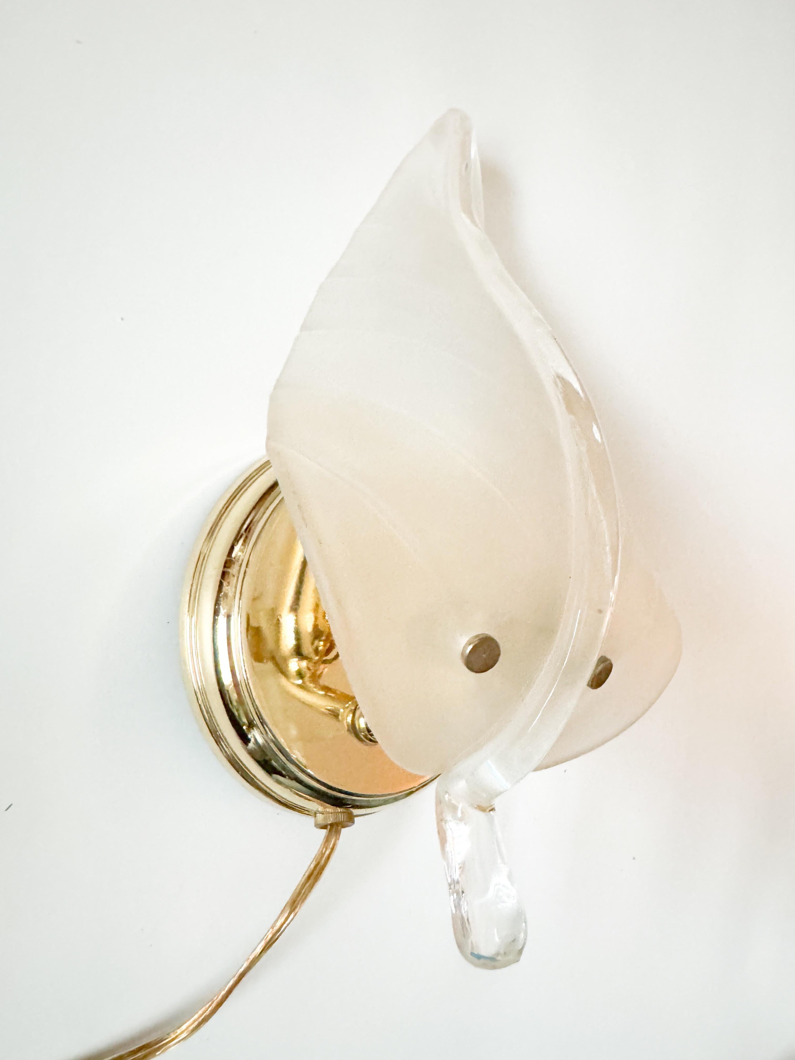 A stunning and sculptural single Murano wall sconce from Italy, dating back to the 1970s. The piece features a beautifully crafted textured glass leaf in a soft, translucent tone that gently diffuses light, creating a warm and ambient glow when lit.