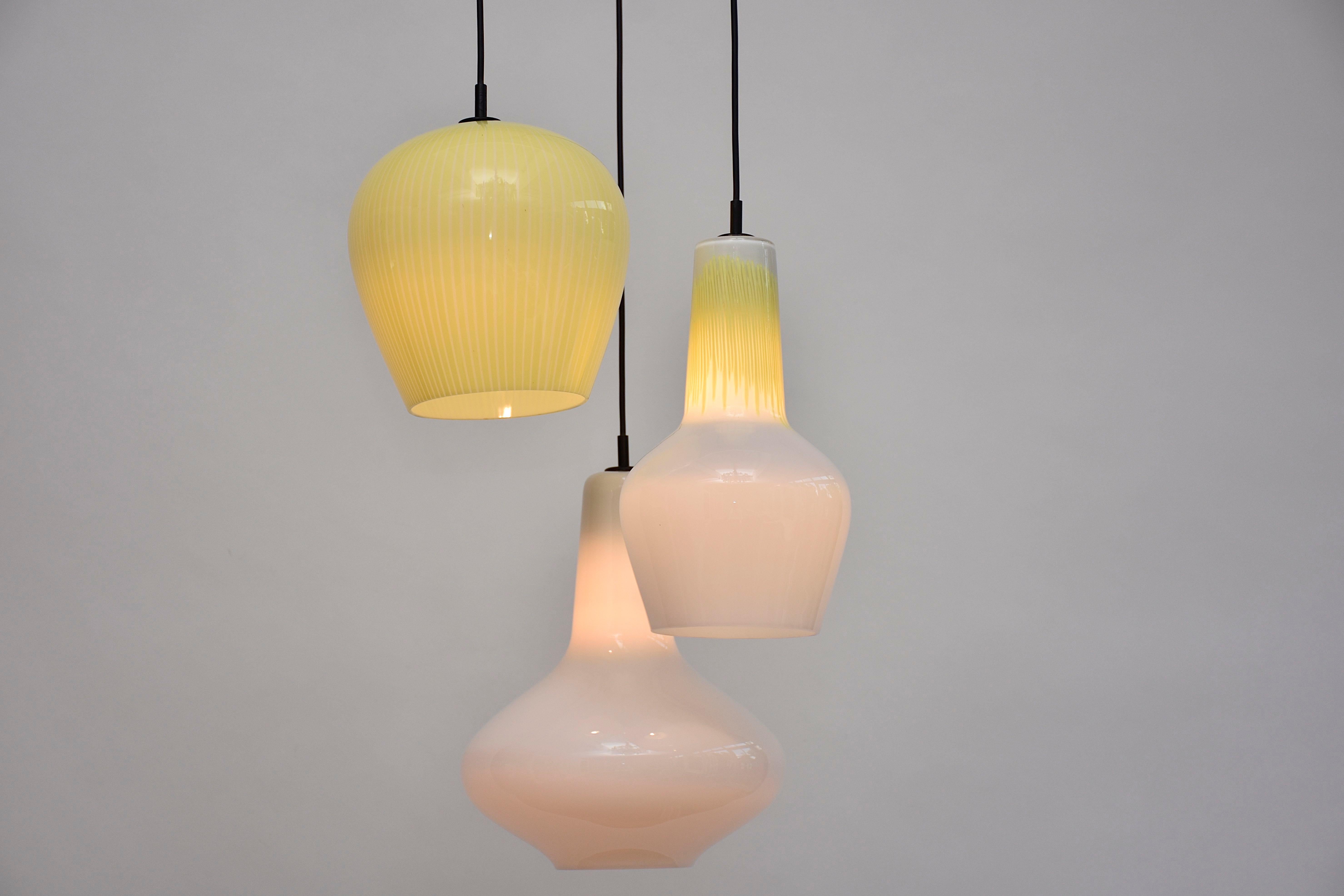 A mid-century original Italian pendant by Massimo Vignelli for Venini Murano.
With 3 hand blown coloured and white Murano glass pendants and polished brass.
The lamp gives a nice diffuse light.

E27 fitting. Suitable for light bulbs/ halogen/