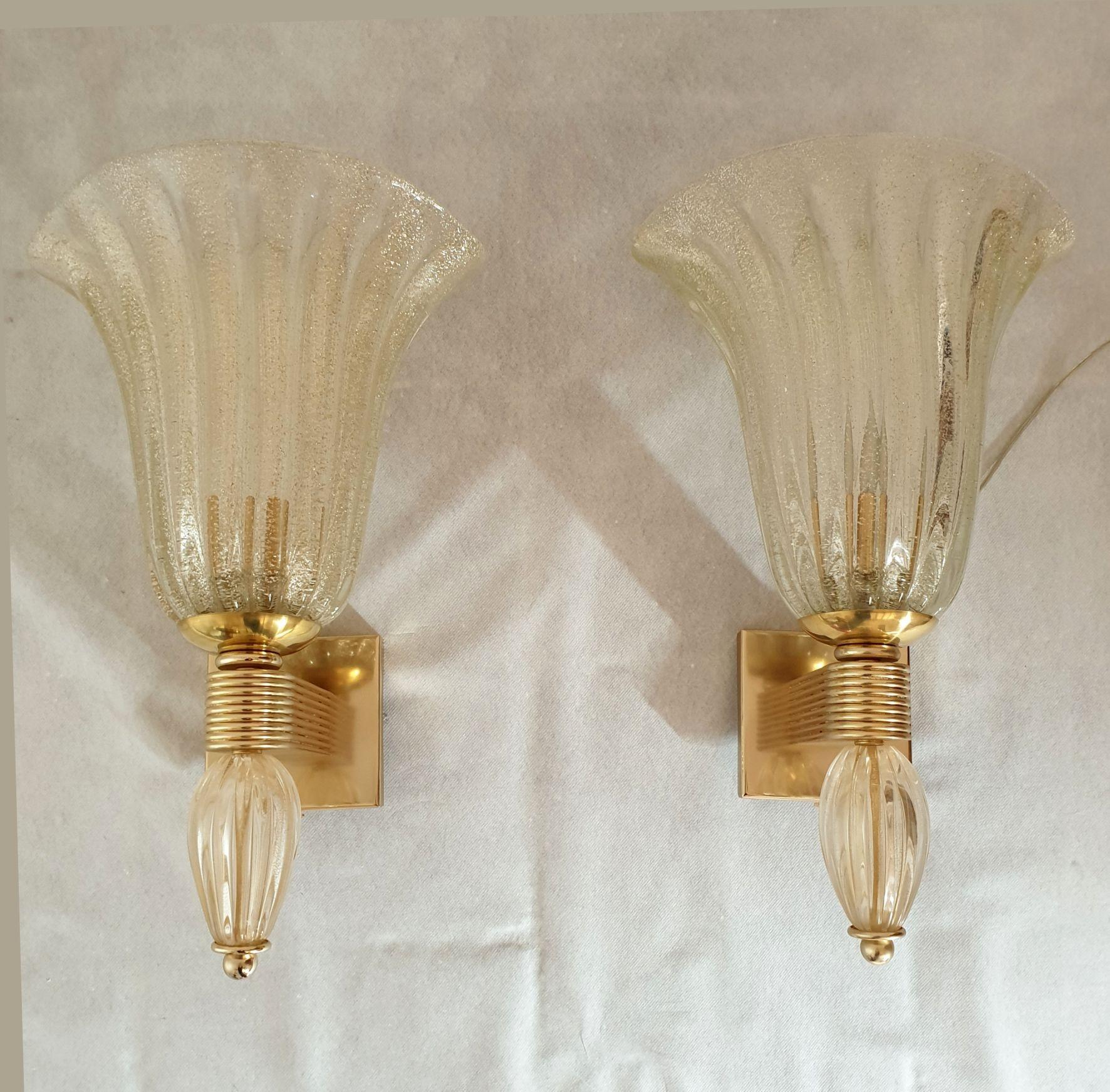 Pair of large Neoclassical style Murano glass sconces, attributed to Barovier & Toso, Italy 1970s.
The Mid-Century sconces are made of hand blown clear and thick Murano glass, with real gold flakes.
The gold flakes inside the Murano glass create a