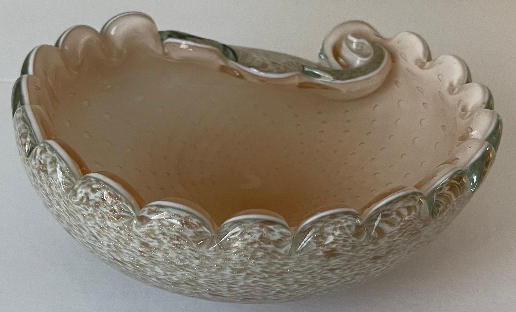 Mid-century Murano glass ashtray. Shell pink glass interior with all over controlled bubbles. Scalloped edges. Outside of bowl is white glass with scattered bronze and gold flecks. No makers mark or signature.