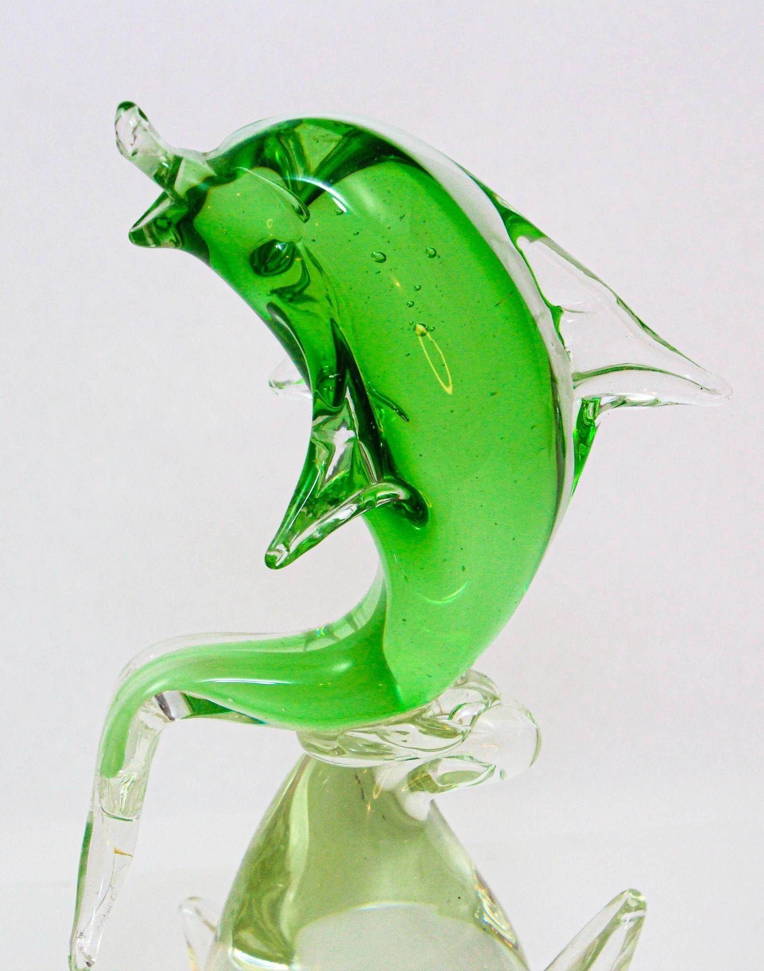 Delfín de cristal soplado verde esmeralda estilo Murano de Italia sobre cristal transparente.
Escultura artística de cristal que representa un delfín verde abstracto en un artístico cristal de Murano sobre una base de olas transparentes.
Escultura