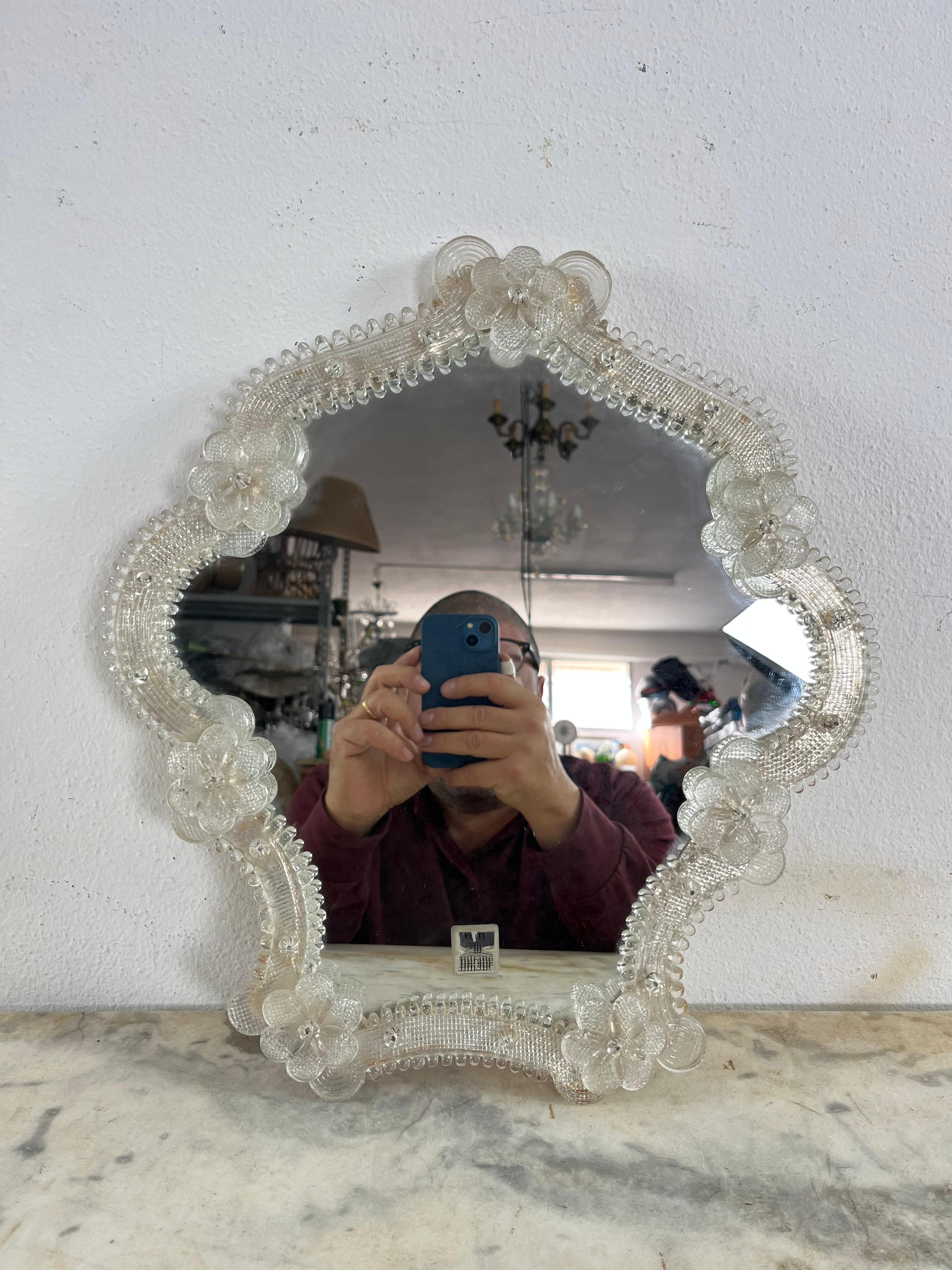 Mid-Century Murano glass wall mirror,  1960s
Intact, good condition, found in a noble apartment in my city, Palermo.
Height 40 cm, width 36 cm.