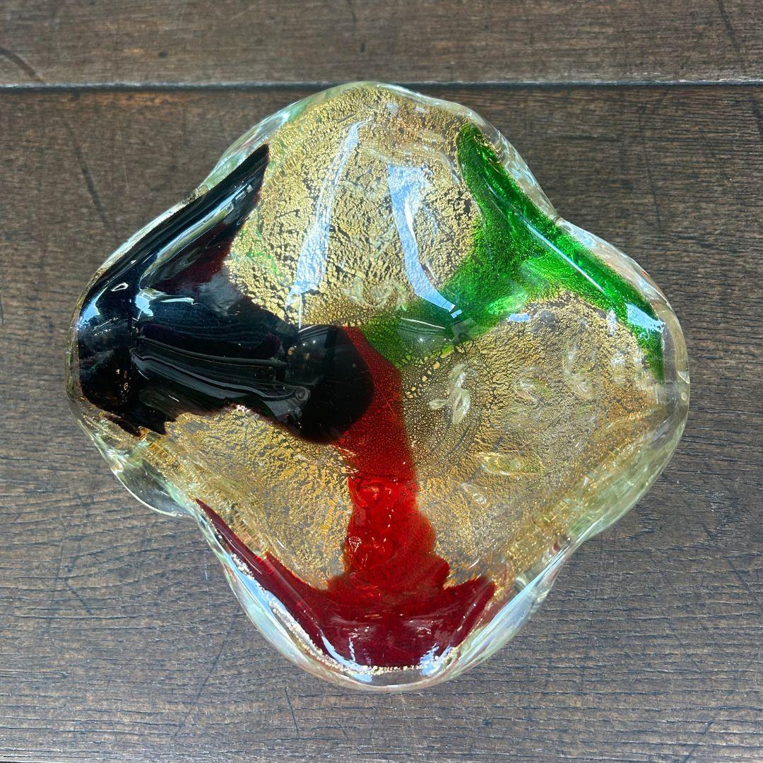 Diese Schale aus mundgeblasenem Murano-Glas zeichnet sich durch reiche Wirbel aus smaragdgrünem, rubinrotem und tiefschwarzem Glas aus, die von schimmernden 24-karätigen Goldflecken akzentuiert werden. Die in Venedig, Italien, gefertigte Schale