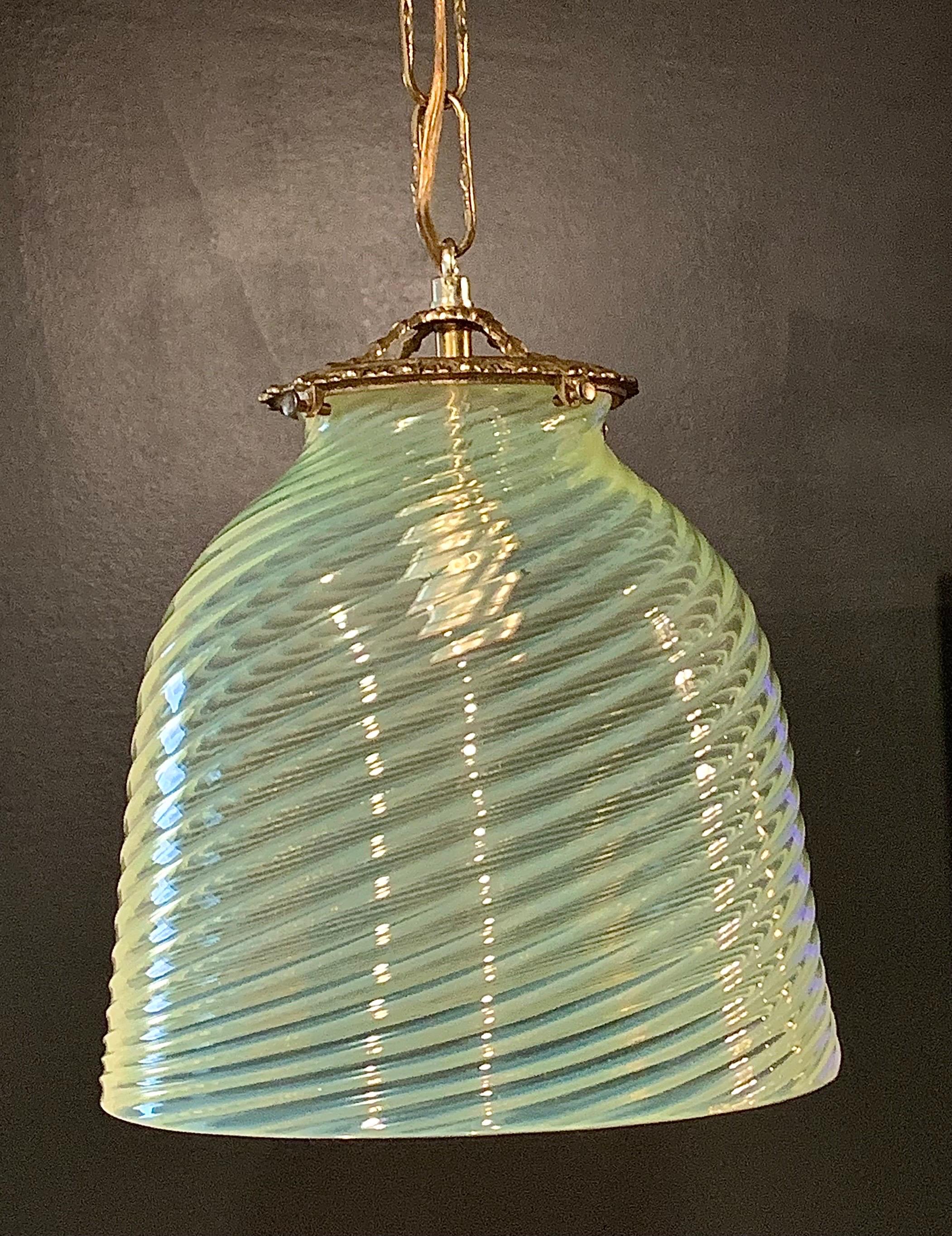 A stunning mid-century opaline murano bell shaped pendency light with brass details. The glass has a stunning swirl design and its s semi transparent yellow /g reen / blue.