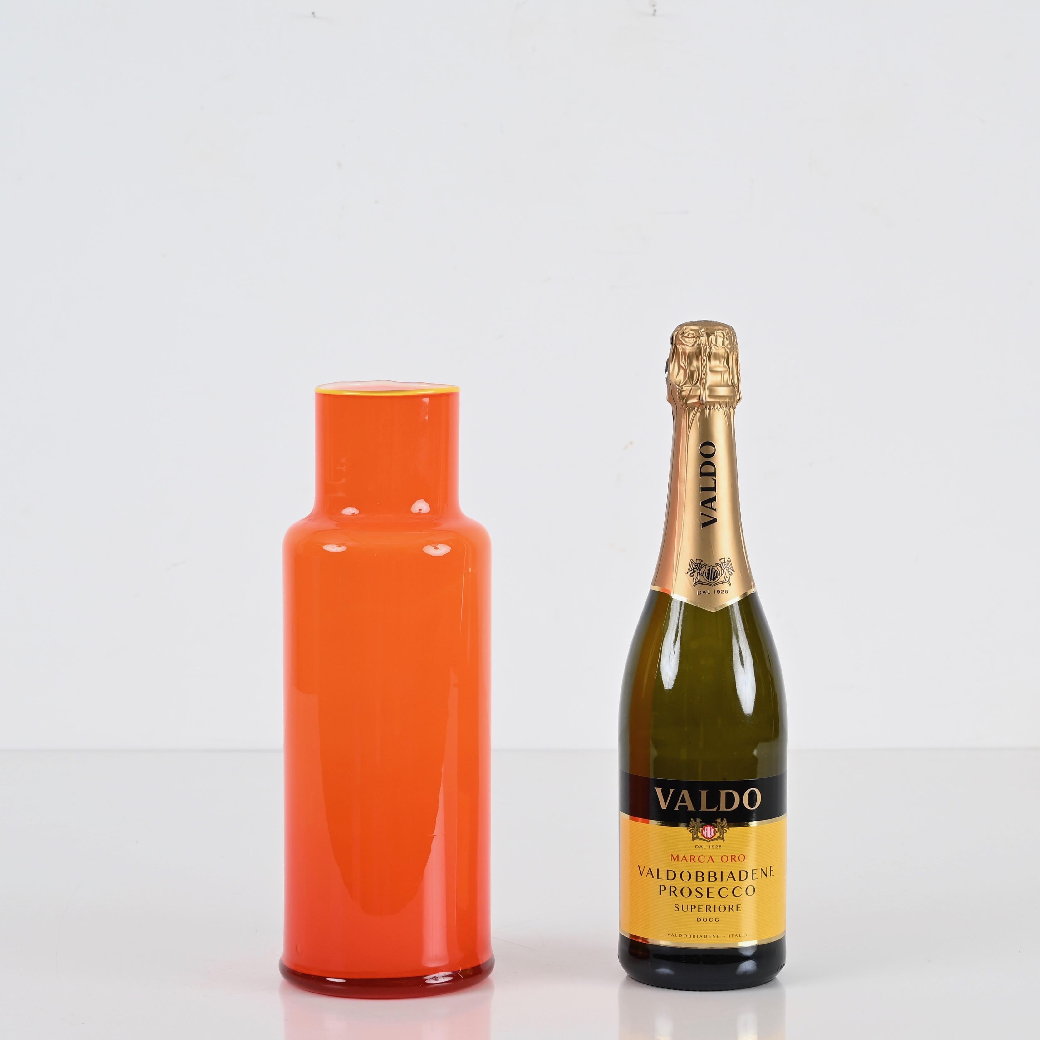 Étonnant vase en verre de Murano du milieu du siècle dans un verre encastré d'un orange vibrant. Cette belle pièce a été réalisée à Murano, en Italie, dans les années 1970.

La qualité du verre encastré et la forme sinueuse de ce vase sont