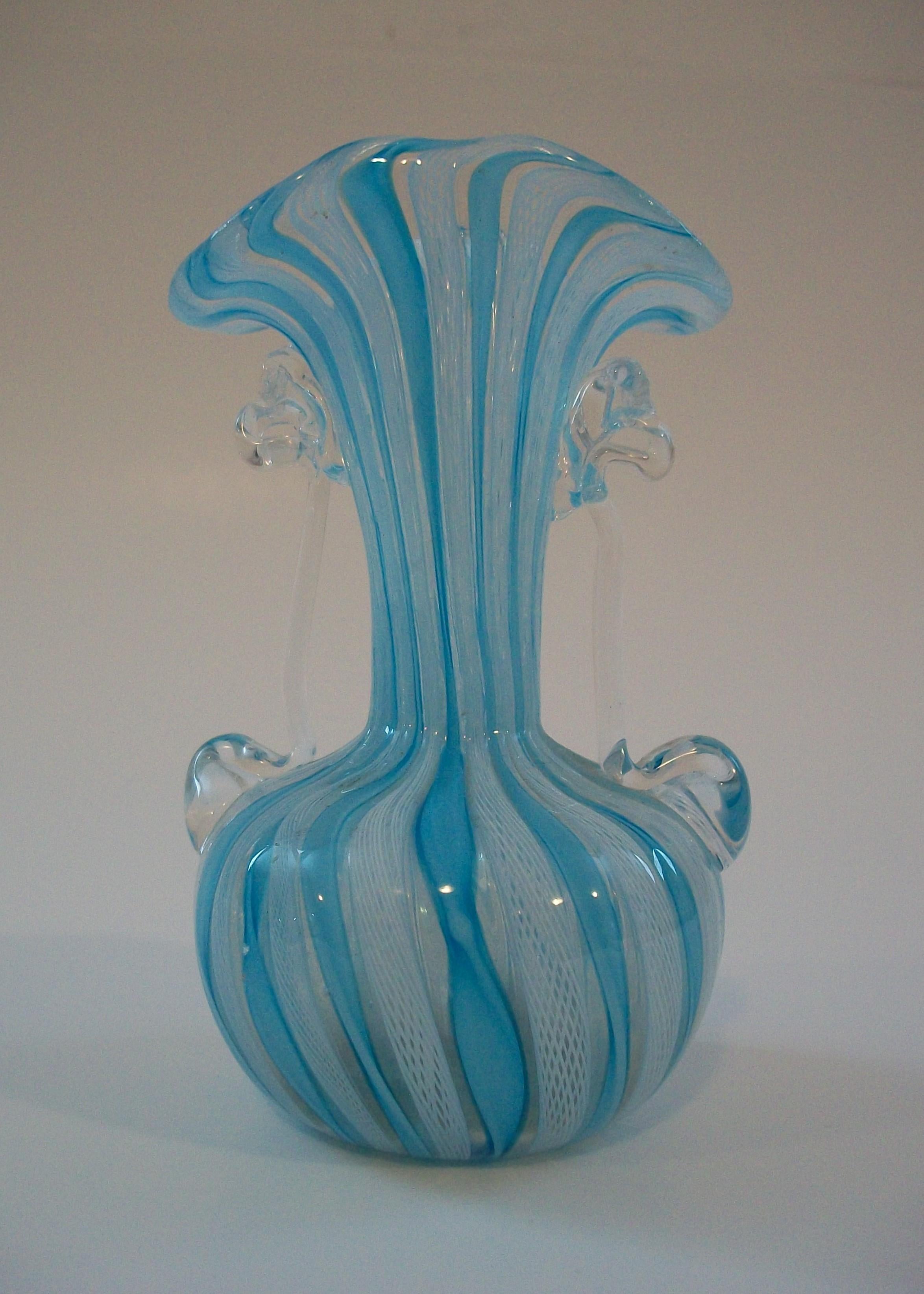 Vaso a due manici in vetro artistico di Murano della metà del secolo scorso - canne di latticino bianche e nastri intrecciati blu con manici in vetro trasparente - peso leggero con finitura lucida - non firmato - Italia - anni '50 circa.

Eccellenti