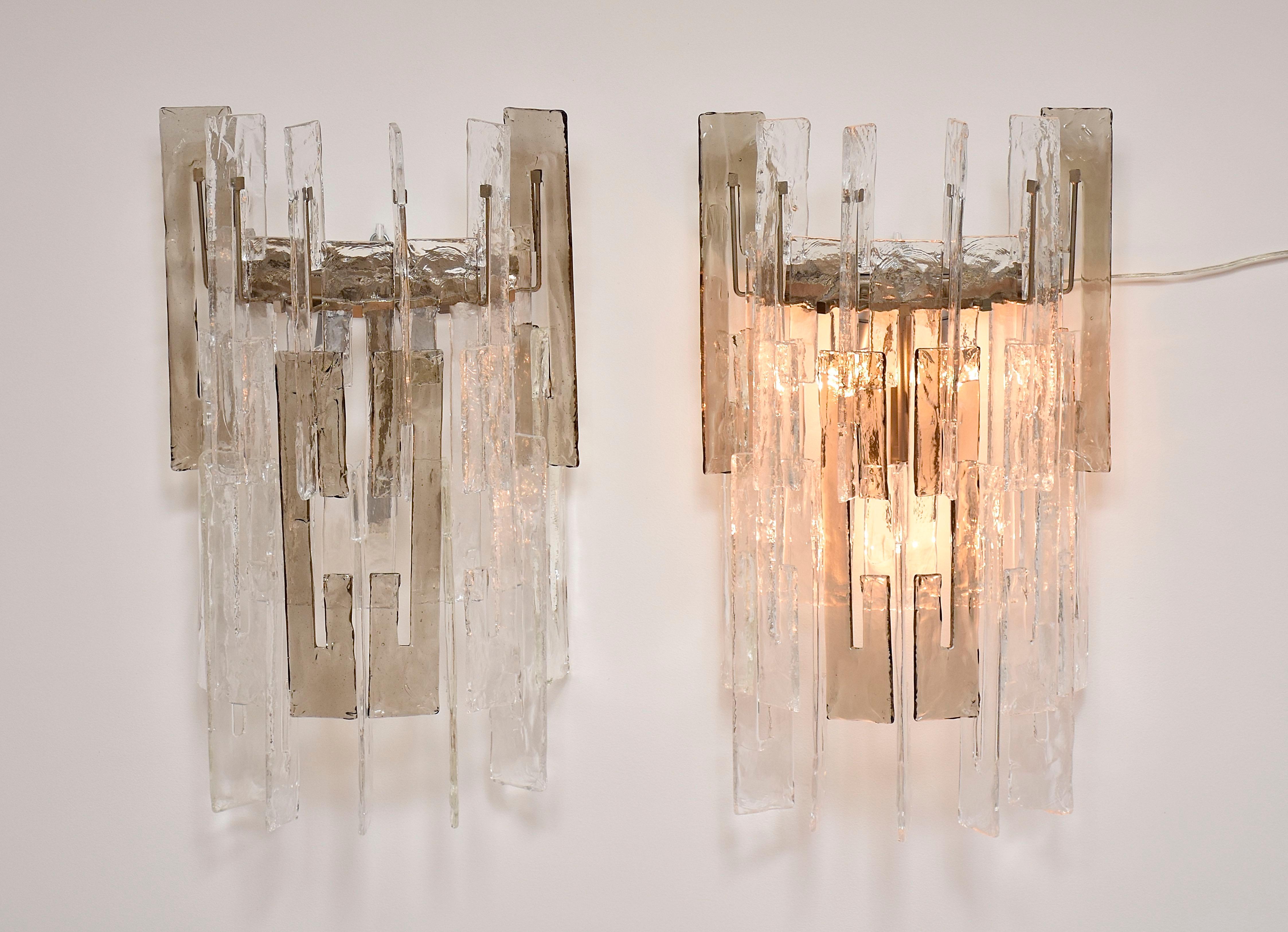 Un hermoso y exclusivo par de apliques grandes de Murano de Mazzega.
Hecho a mano; Fabricado con elementos de cristal de Murano transparente y ahumado, un diseño icónico de Carlo Nason - cada elemento de Murano tiene forma de letra 