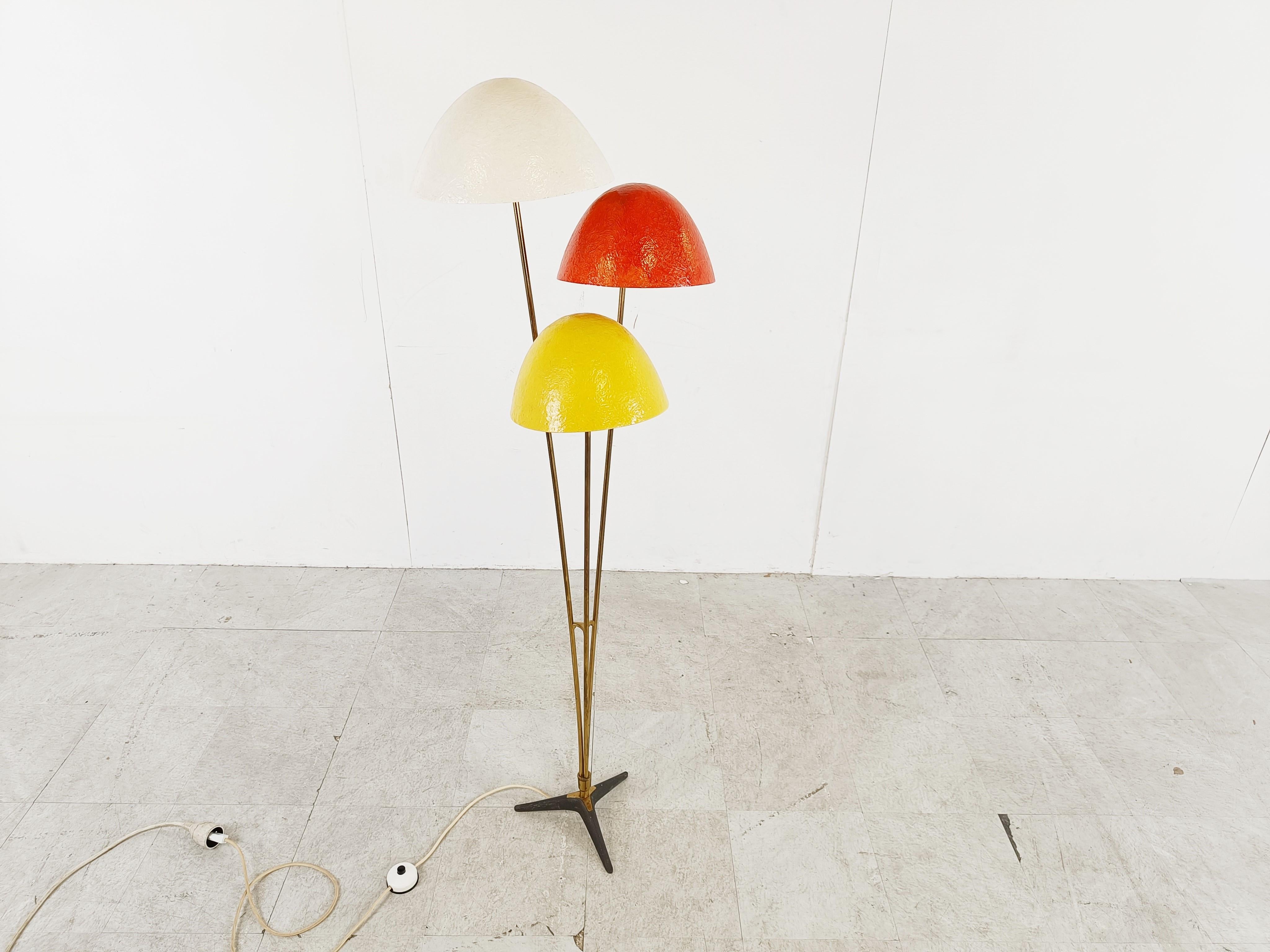 Bunte, pilzförmige Stehlampe aus der Mitte des Jahrhunderts mit drei Lampenschirmen aus Fiberglas, montiert auf einem Messinggestell mit schwarzem Metallsockel.

Sehr elegantes Design.

Die Leuchte strahlt ein warmes Licht aus.

Geprüft und