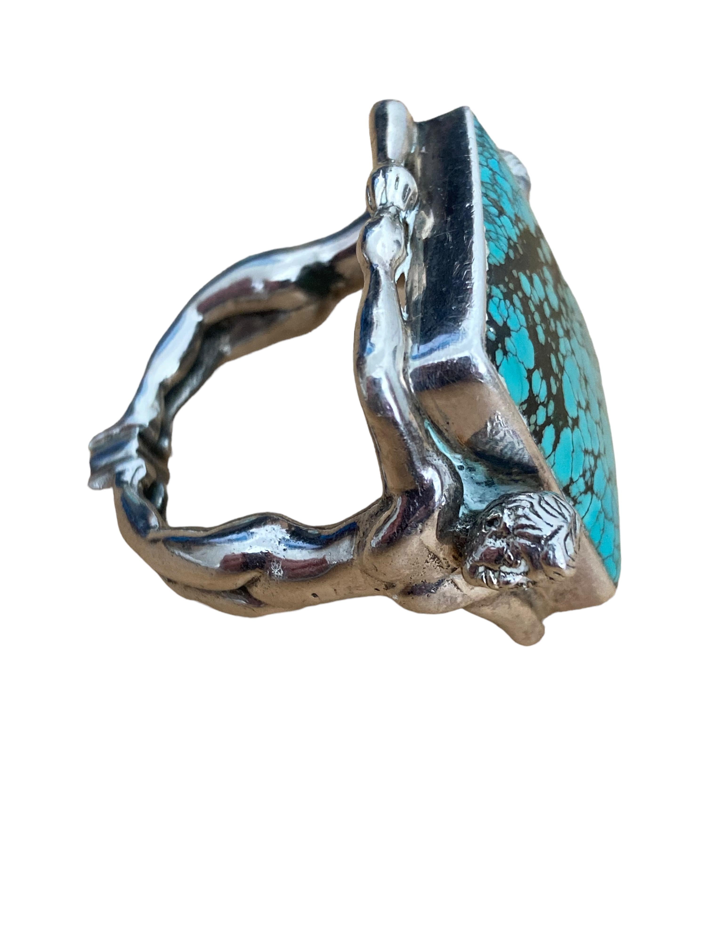 This Native American Sterling Silver and Turquoise Ring has a maker's mark and appears to be dated 1958. One side of the shank is a man and the other is a woman. They have joined hands on either side of the ring and complete the shank with touching