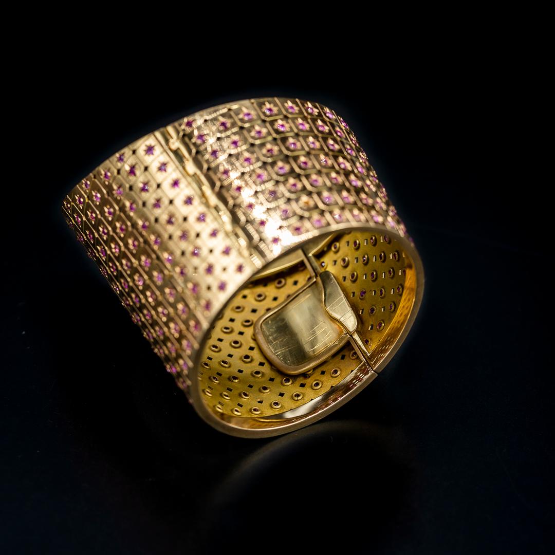 Mid-Century natural unheated Burmese ruby bangle bracelet in rose gold, 1950s/1960s. This jewel is designed with two hinged halves, creating a seamless fit. The front half, slightly larger, elegantly tapers down from the center, forming a