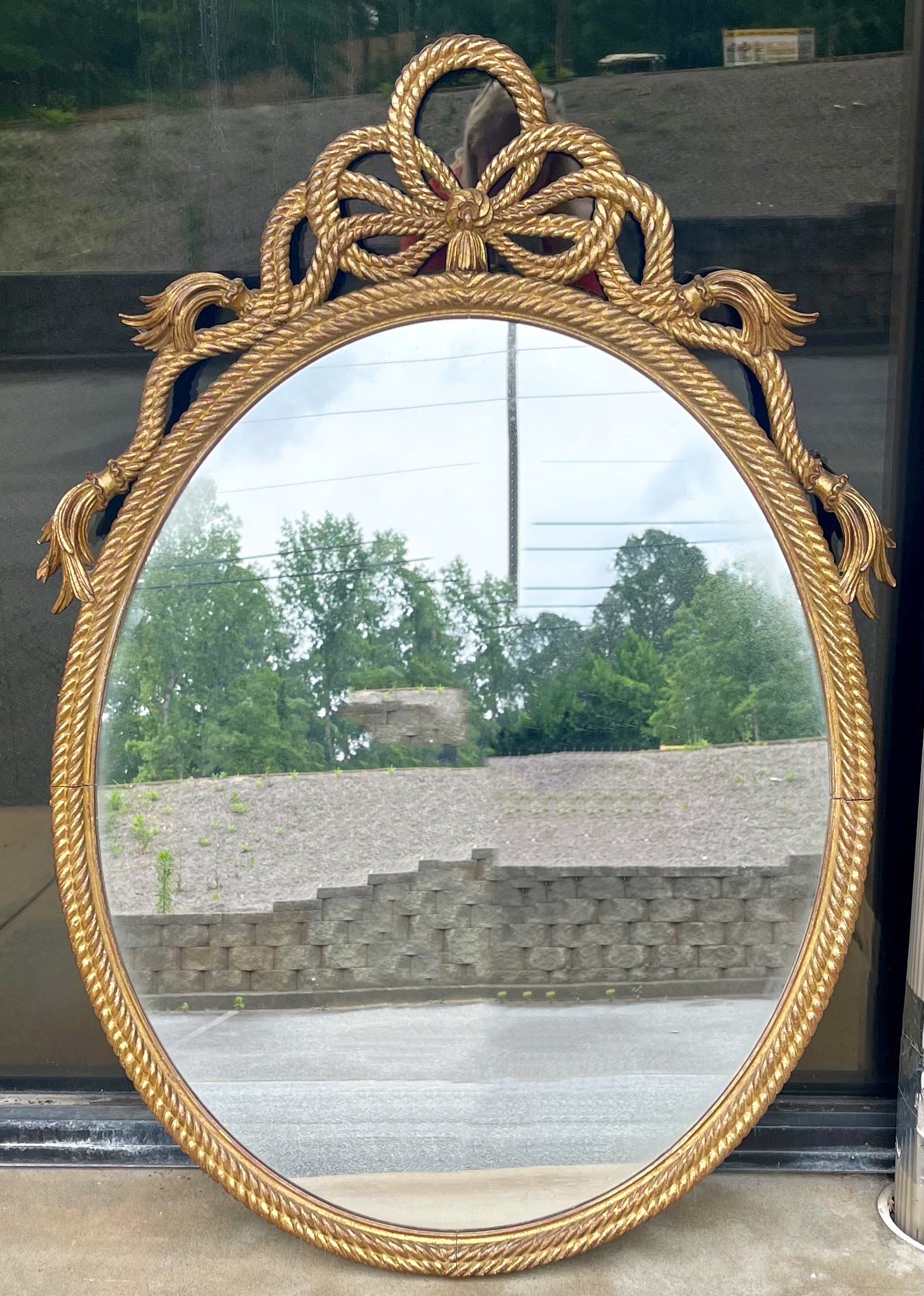 I love this one. It is an Italian carved giltwood mirror with a tassel and rope motif. It has timeless neo-classical styling. The mirror is unmarked and most likely date to 1960.