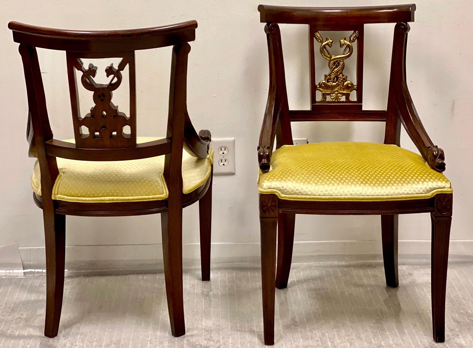 This is a pair of midcentury mahogany and gilt chairs that are attributed to Baker Furniture. The yellow upholstery is new. The carved dolphin and arrow backs are highlighted in gilt paint. They are in very good condition.