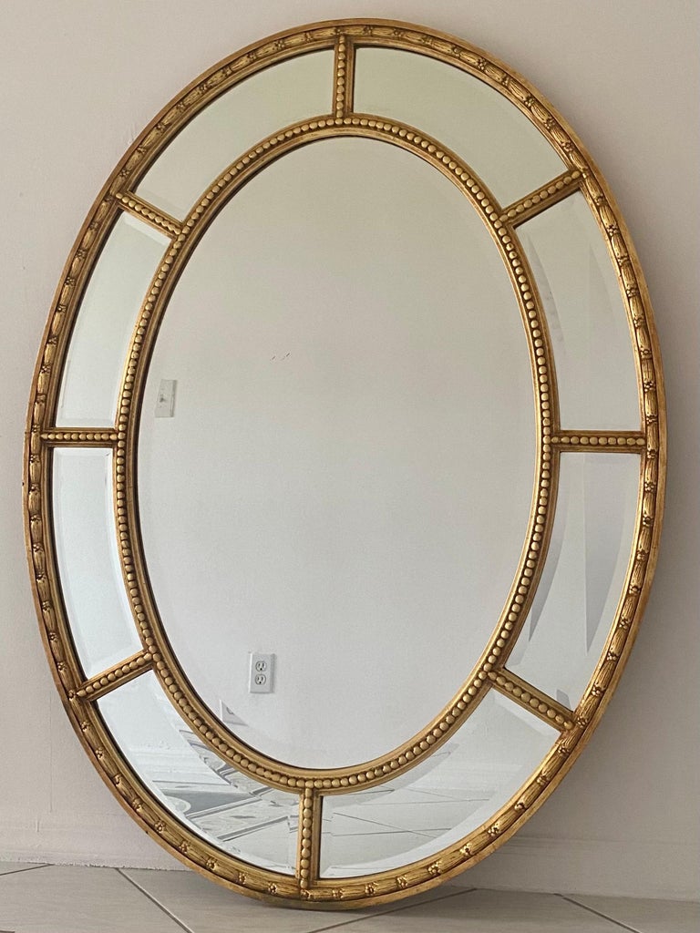 Stunning oval gilt wood frames multiple beveled mirrors in this circa 1950s Neoclassical Palm Beach Estate piece. The Mirror is in very good condition.