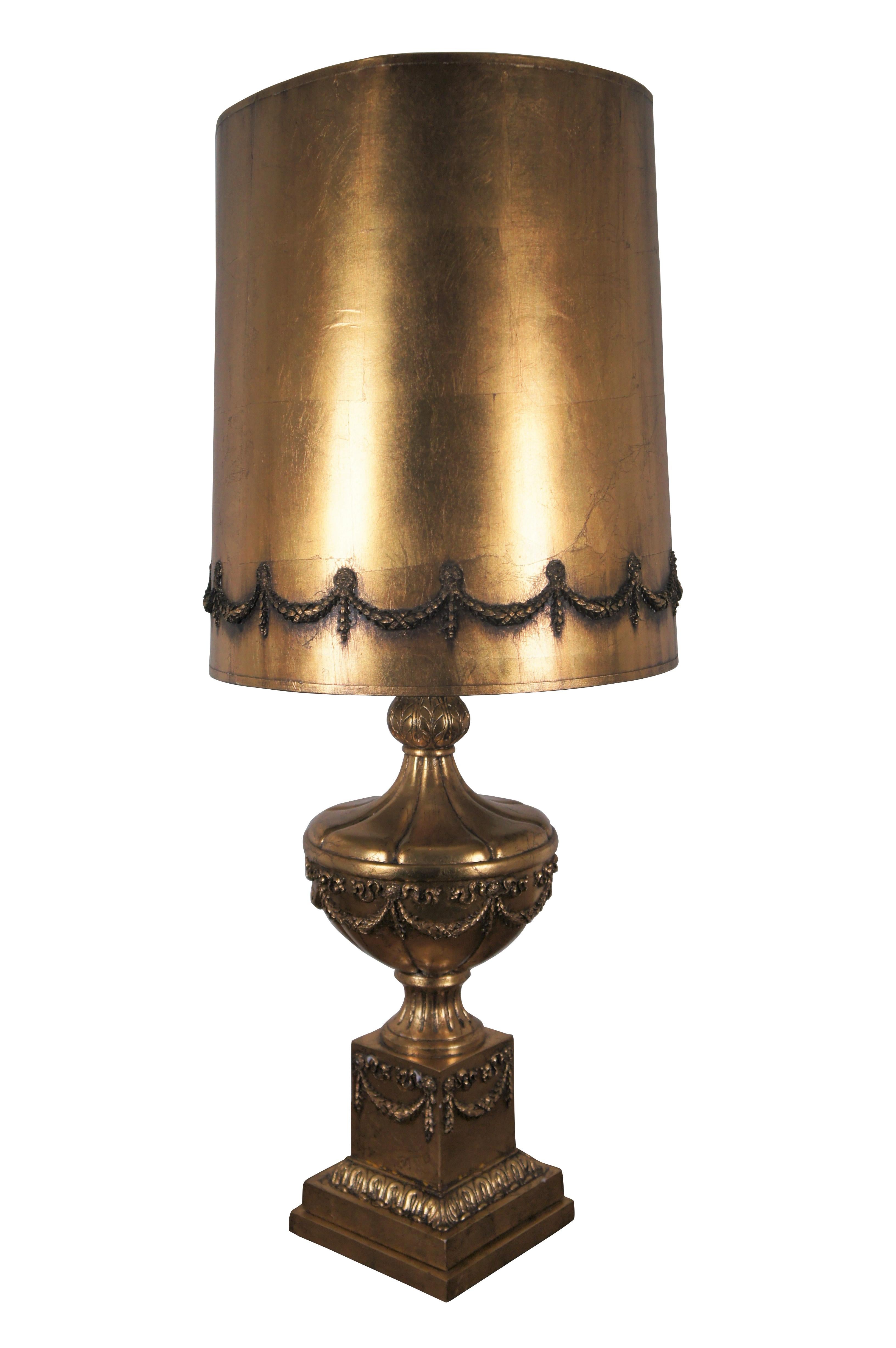 Vintage mid-20th century Hollywood Regency / Neoclassical French resin table lamp with three way switch. The golden base is in the shape of a fluted urn mounted on a pedestal, decorated with ribbons and foliate swags, crowned in a globe of leaves.