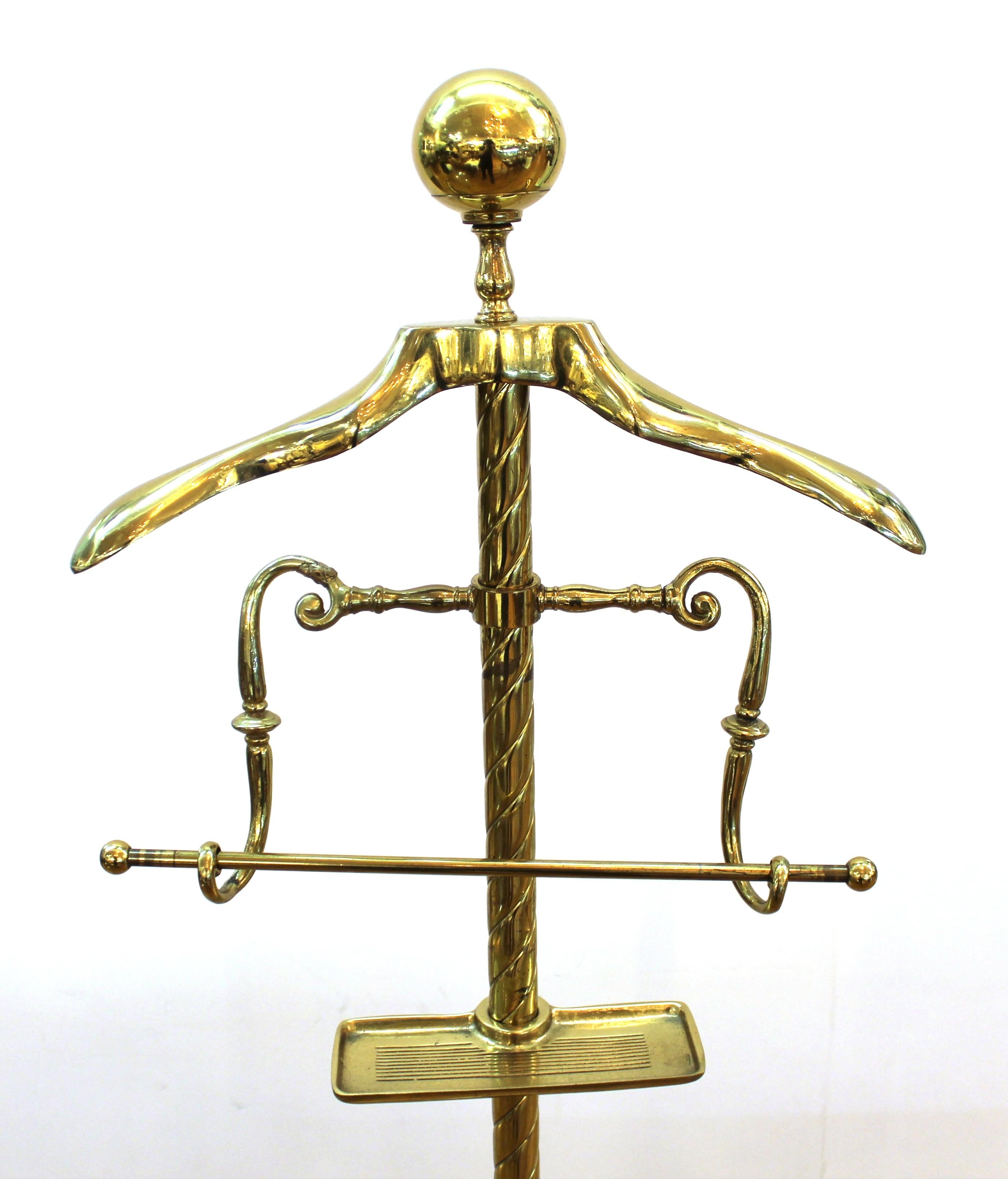 Mid-century neoclassical style brass valet with adjustable hanger and vide-poche elements.