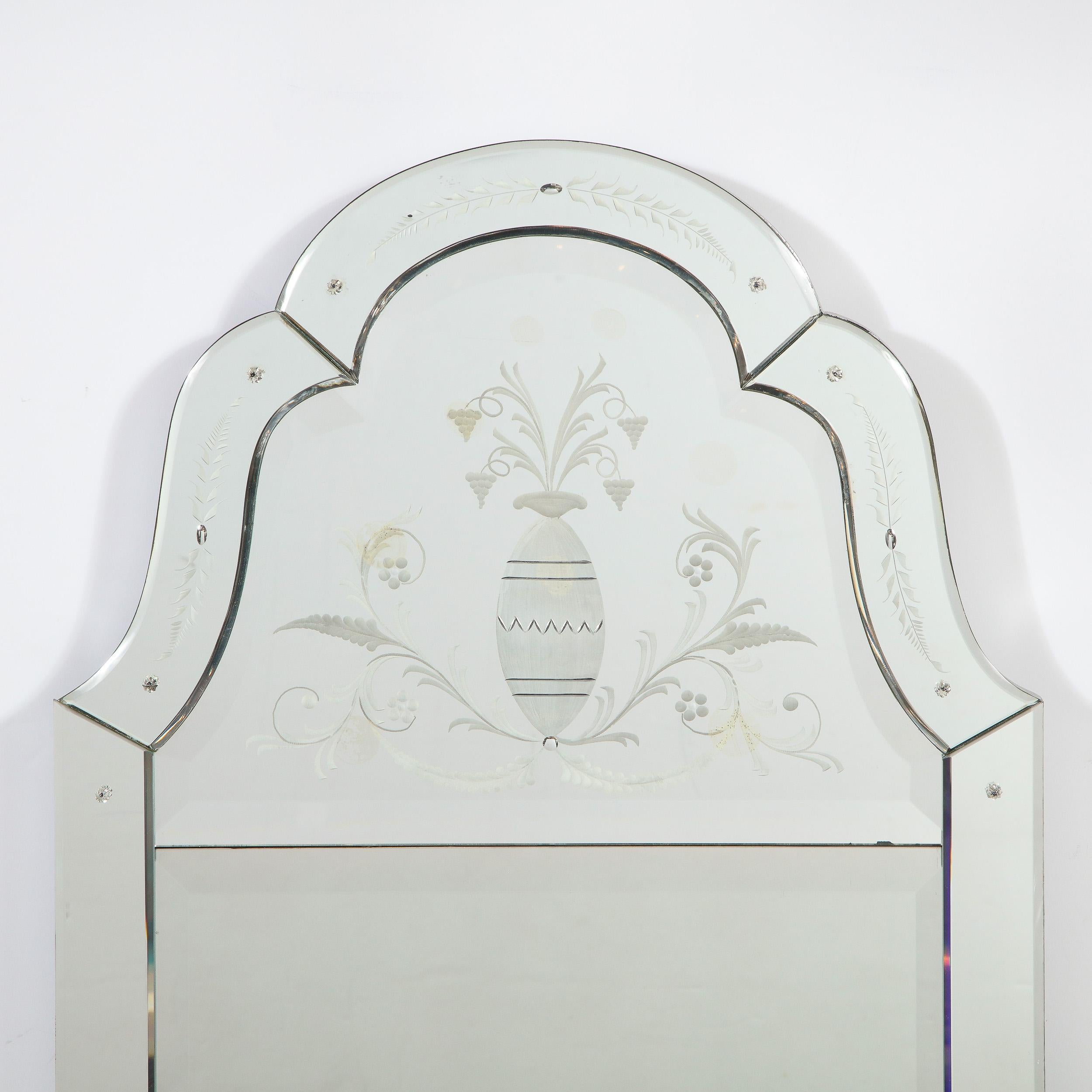 This elegant Mid-Century Modern mirror was realized in the United States, circa 1950. It features a rectangular form with a scalloped top; and a rectangular center panel of plain mirror topped with a domed panel etched with a neoclassical design.