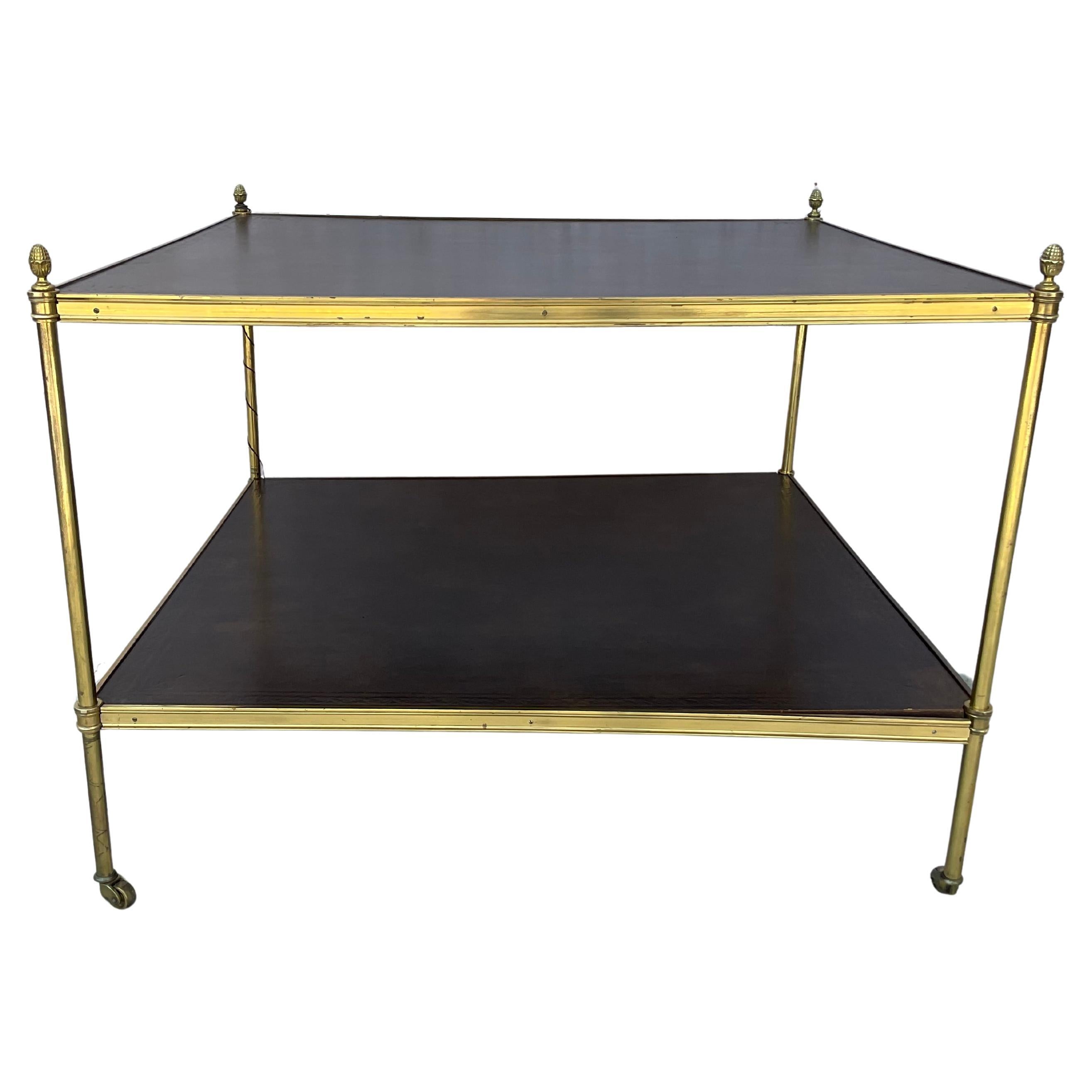 Mid-20th Century French Brass And Leather Side Table. Square table features leather inserts on the two shelves, and acorn finials. The four acorn finials cap each of the legs as a nice ornamental touch. A refined and bold look balancing functional