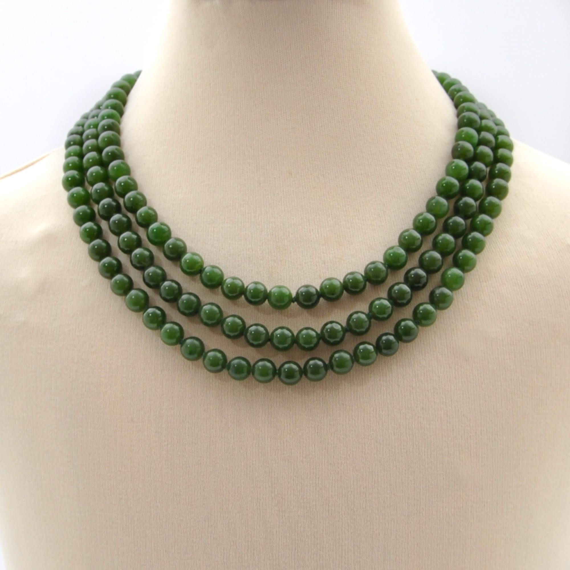 A mid-century dark green nephrite jade three-strand beaded necklace. The necklace consists of round-shaped nephrite jade stones. These jade beads have a very nice green color and are equally sized. To keep some space between the beads, the thread is