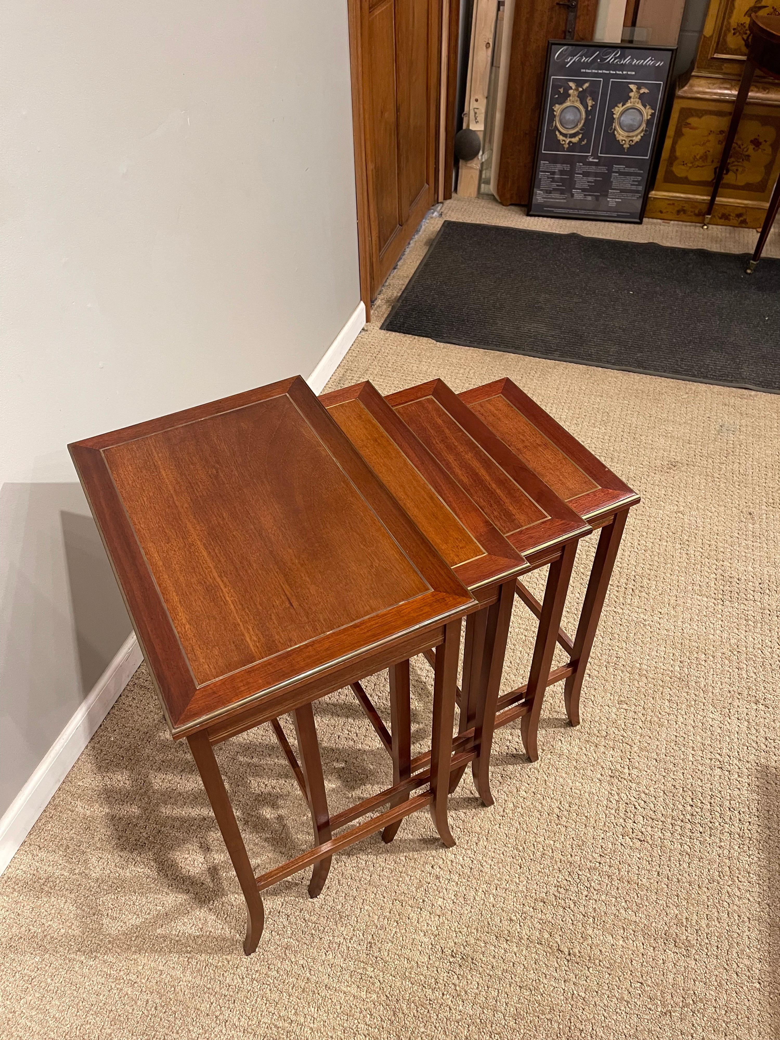 Mid-Century Modern mahogany nesting tables. With brass clad moldings and brass in inlay.