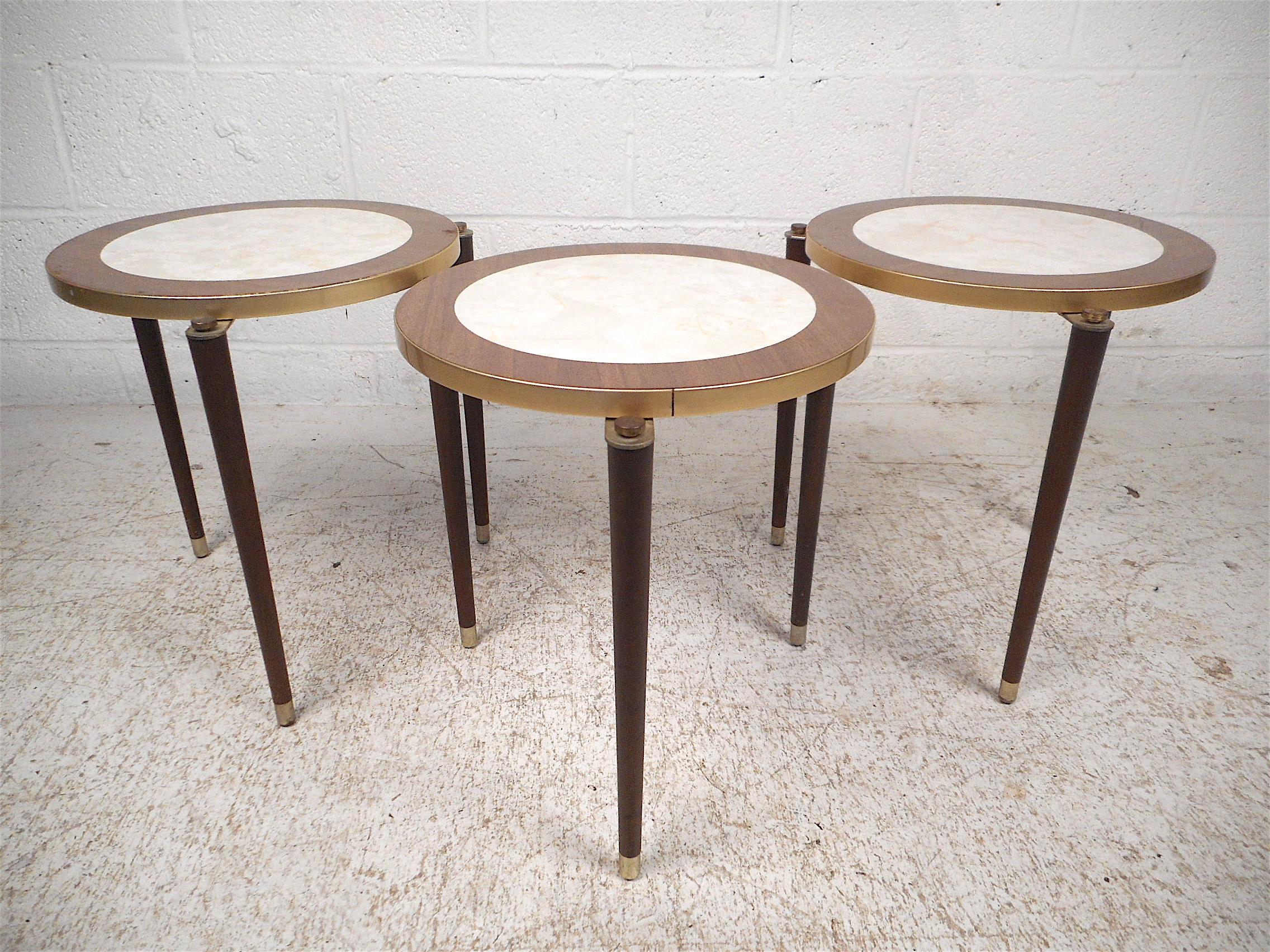 Stylish midcentury nesting tables. Decorative metal trim around the sides and on the feet, tapered legs and inlaid tabletops. Tables stack neatly saving space when not needed. Handy and good-looking addition to any modern interior. Please confirm