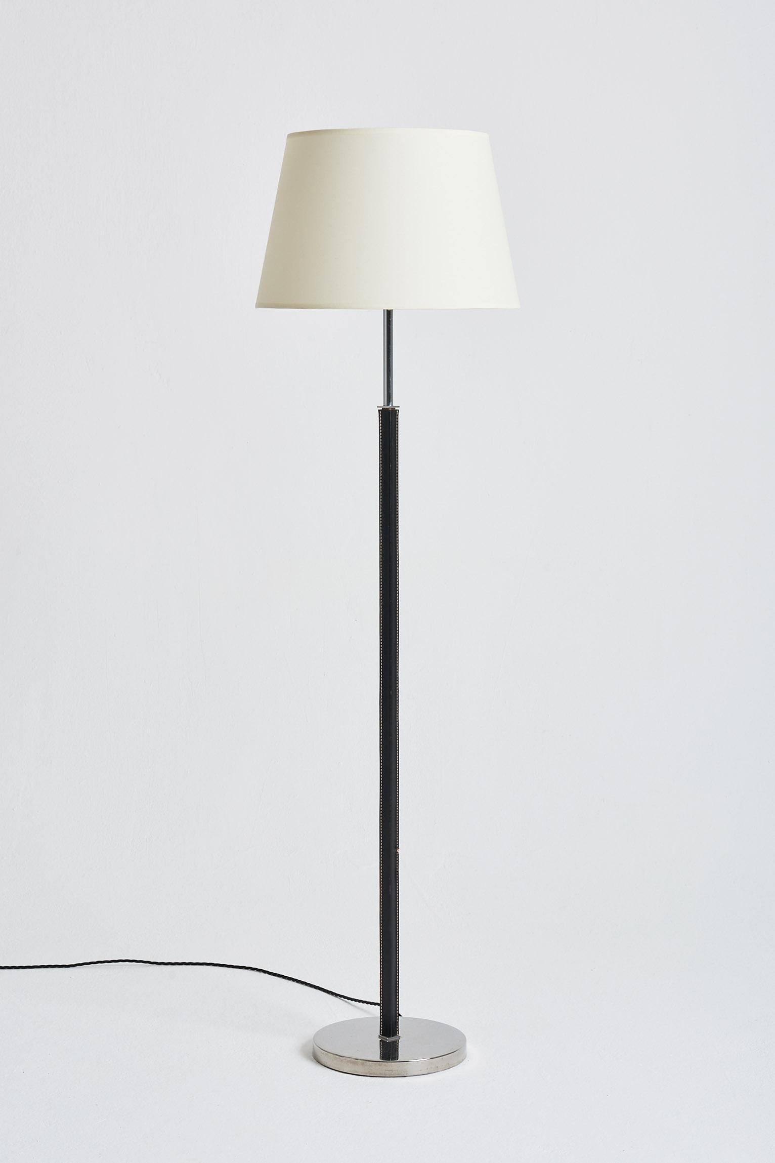 A nickel and saddle stitched black leather floor lamp, by Falkenbergs Belysning. 
Sweden, third quarter of the 20th Century.
With the shade: 147 cm high by 41 cm diameter.
Lamp base only: 127 cm high by 25 cm diameter.
