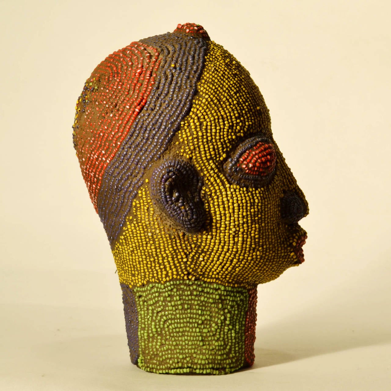 Brightly colored beaded terracotta head commissioned in the 1960's to decorate wealthy Nigerian homes. The terracotta sculpture is inlaid with strings of beads over its ceramic form.
They sometimes came in pairs as man and women or two females.
The