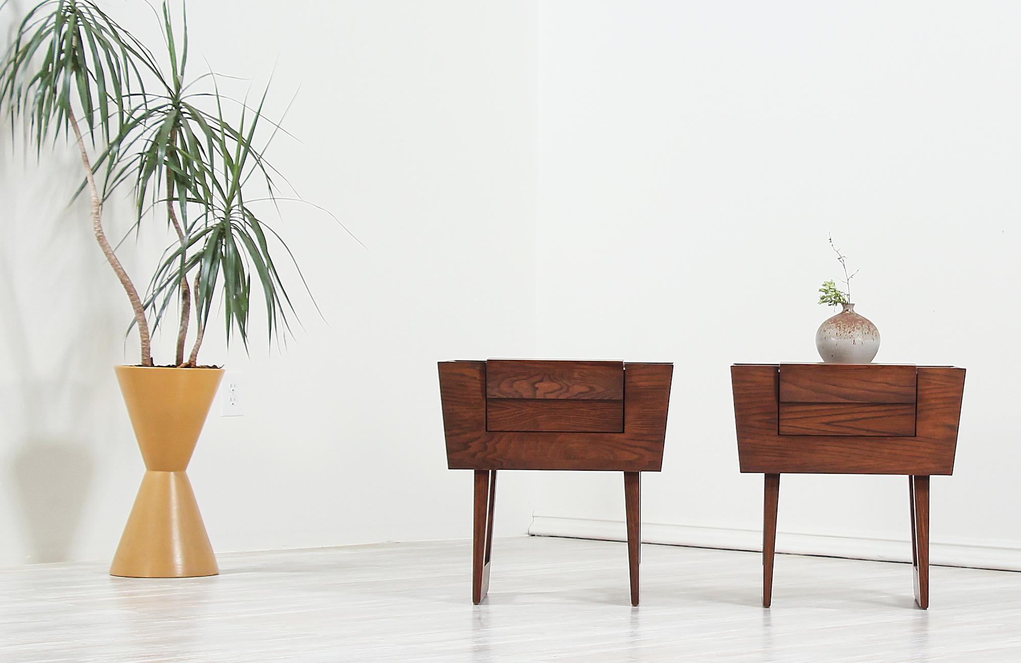 A pair of elegant modern nightstands designed by Paul Laszlo for Brown Saltman in the United States, circa 1950s. This fabulous rare to find pair of night stands are built on solid walnut-stained oak wood featuring a finished back and a single