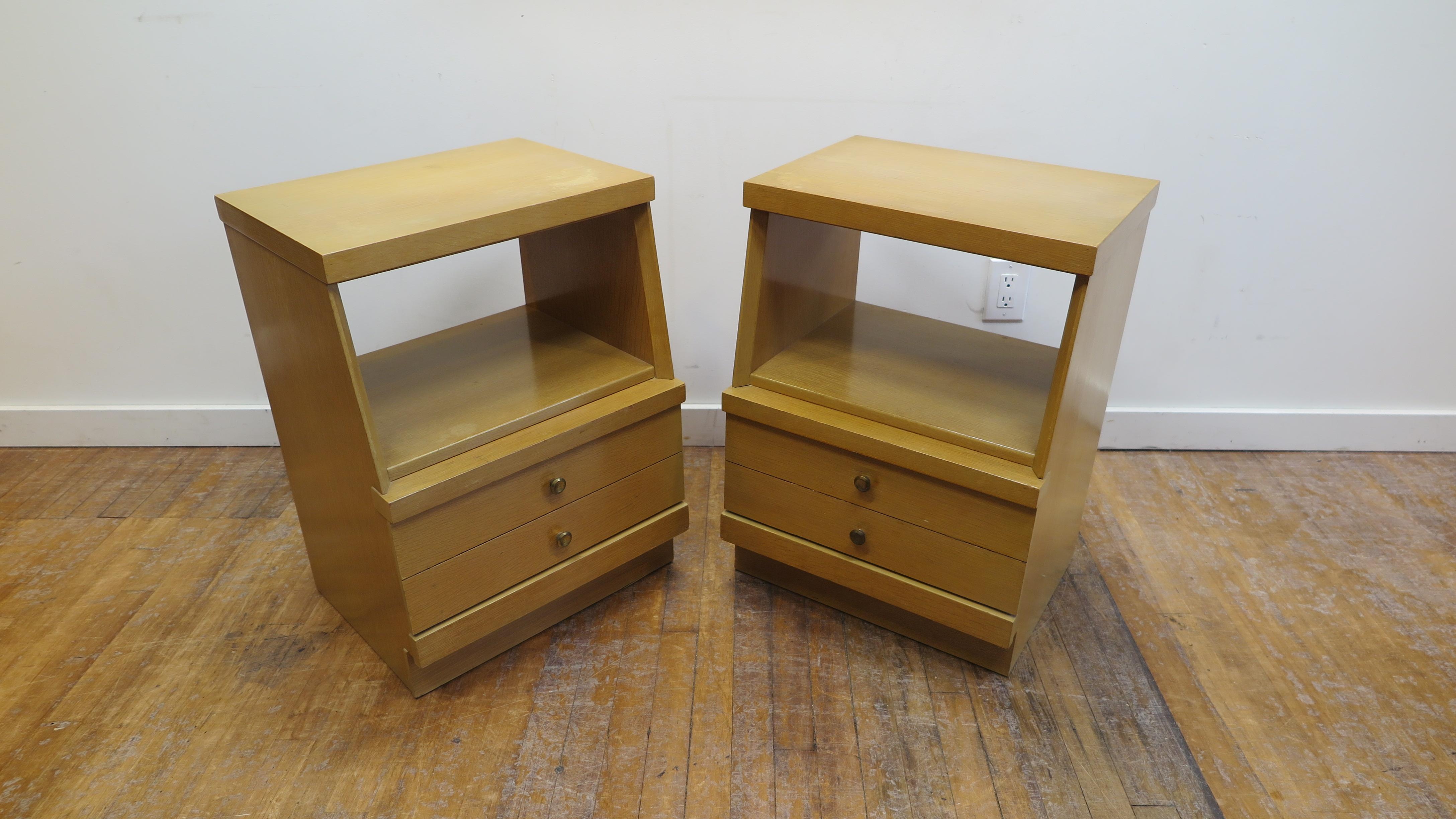 Pair of mid century night stands. Two golden oak colored night stand and or side tables, end tables. Clean lines with tops set back angled profile stance. Having middle shelf and one lower drawer with brass pulls. In good to fair condition, some