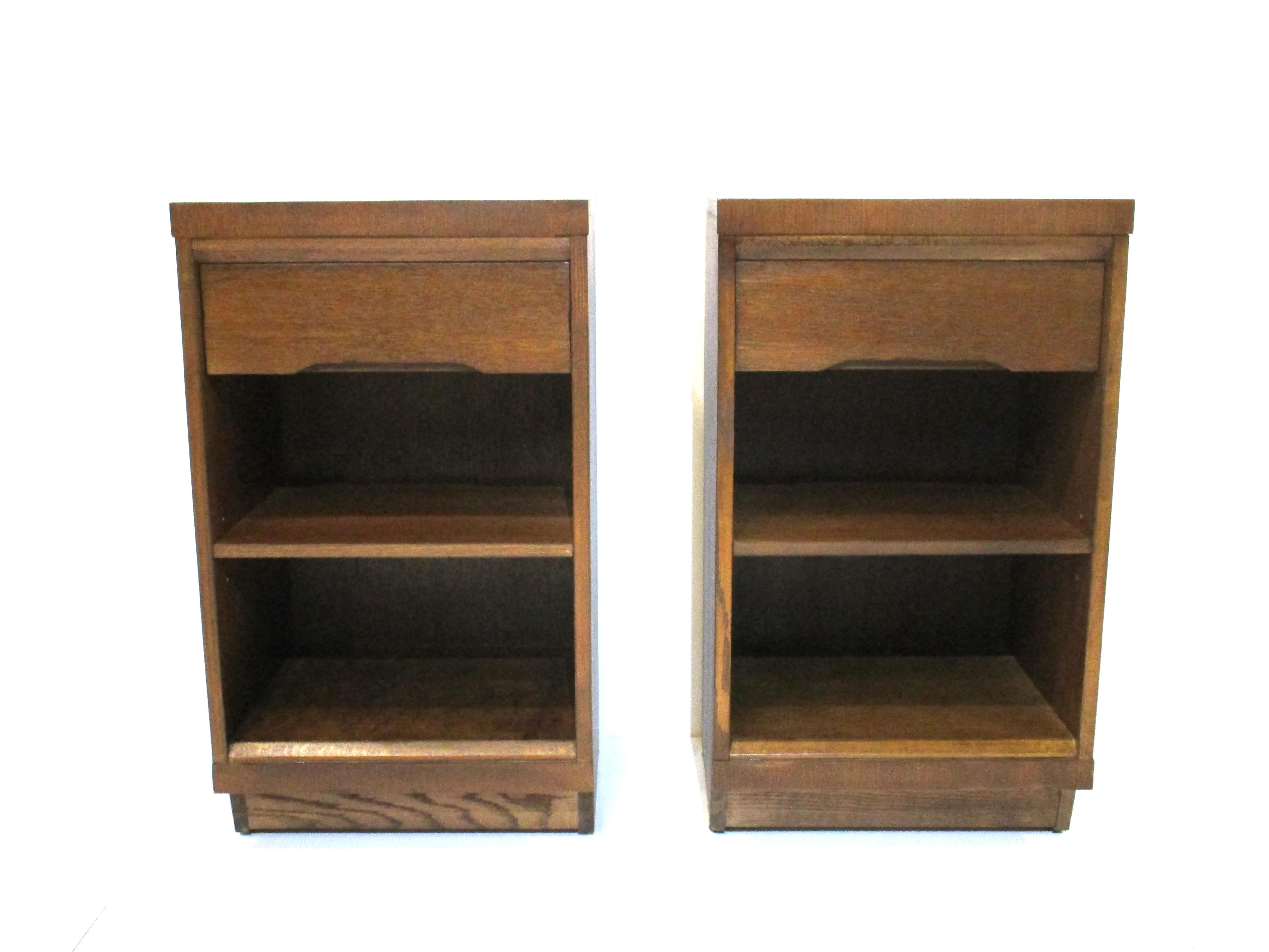 A pair of oak nightstands in a medium dark tone with upper drawer and an adjustable shelve to the mid section. These are in a higher size perfect for today's modern bedding .