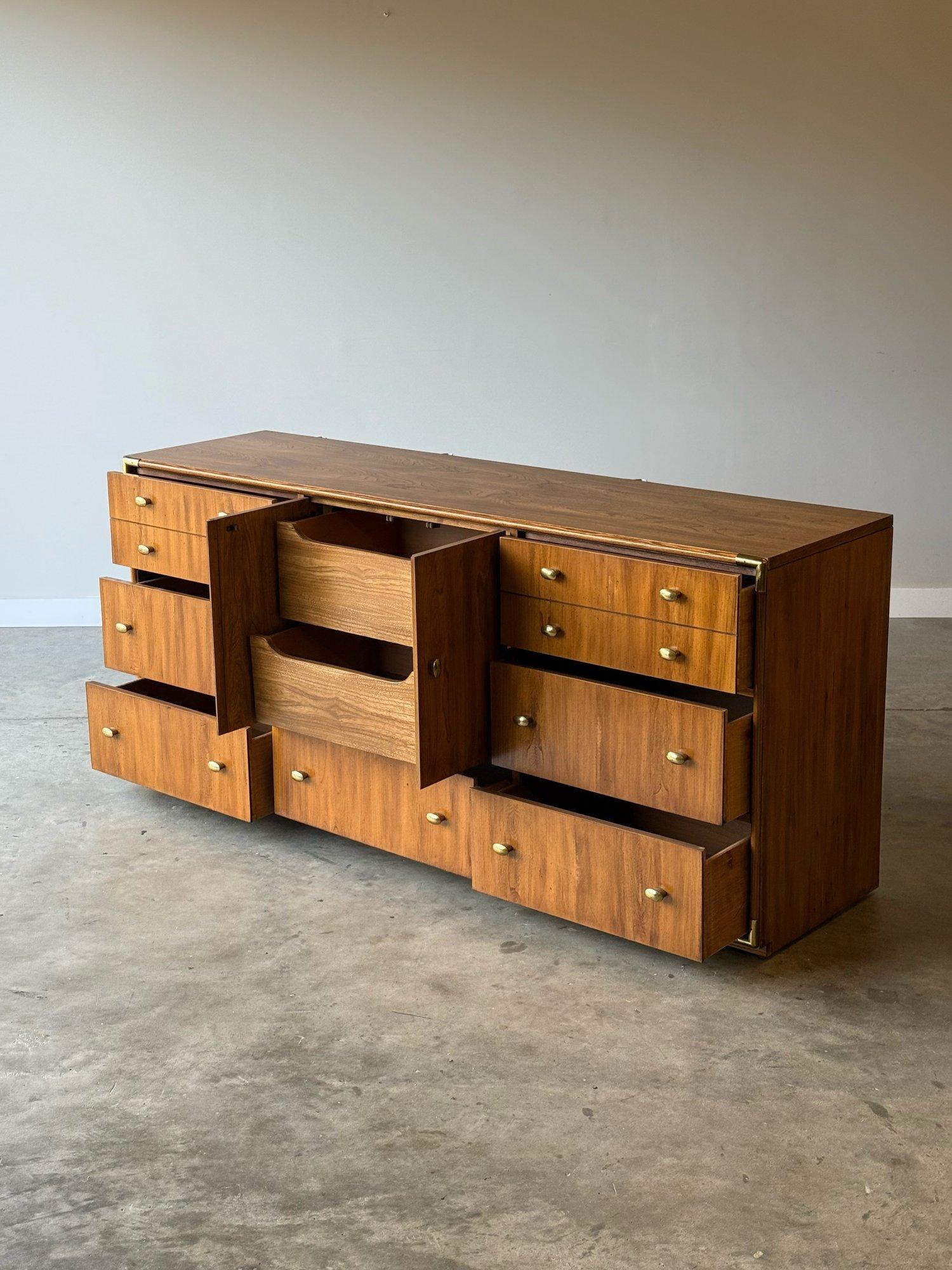 Vintage campaign style dresser manufactured by Stanley Furniture. This dresser combines the rustic sensibilities and brass corners of the campaign style with rounded brass handles reminding us of the Hollywood Regency style. The light wood tone with