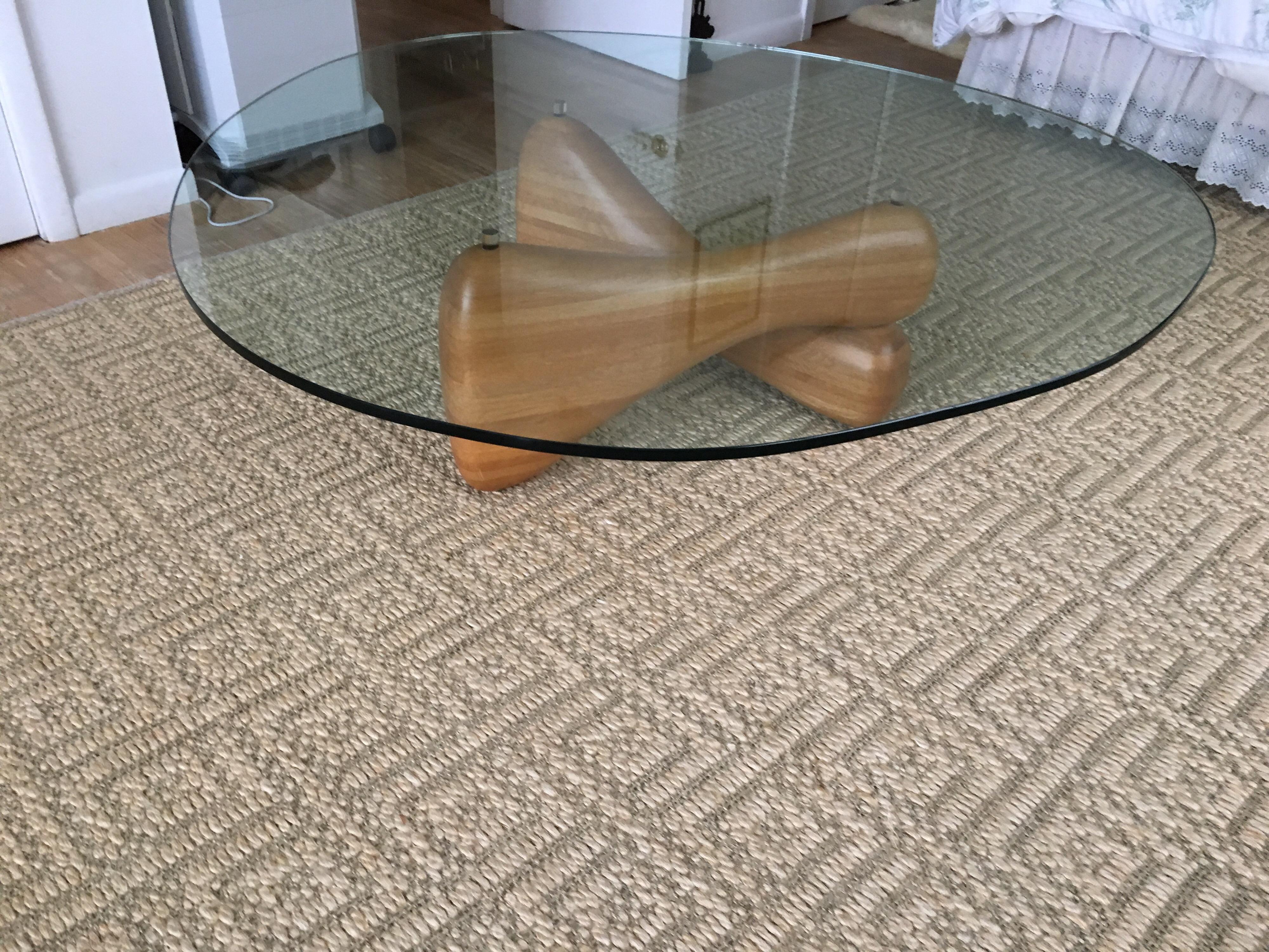 Midcentury Noguchi style biomorphic glass coffee table. This 1970s biomorphic, sculptural coffee table, in the style of Isamu Noguchi.
Articulating biomorphic wood shaped base with plexi mounts to hold biomorphic shaped glass top.
Originally