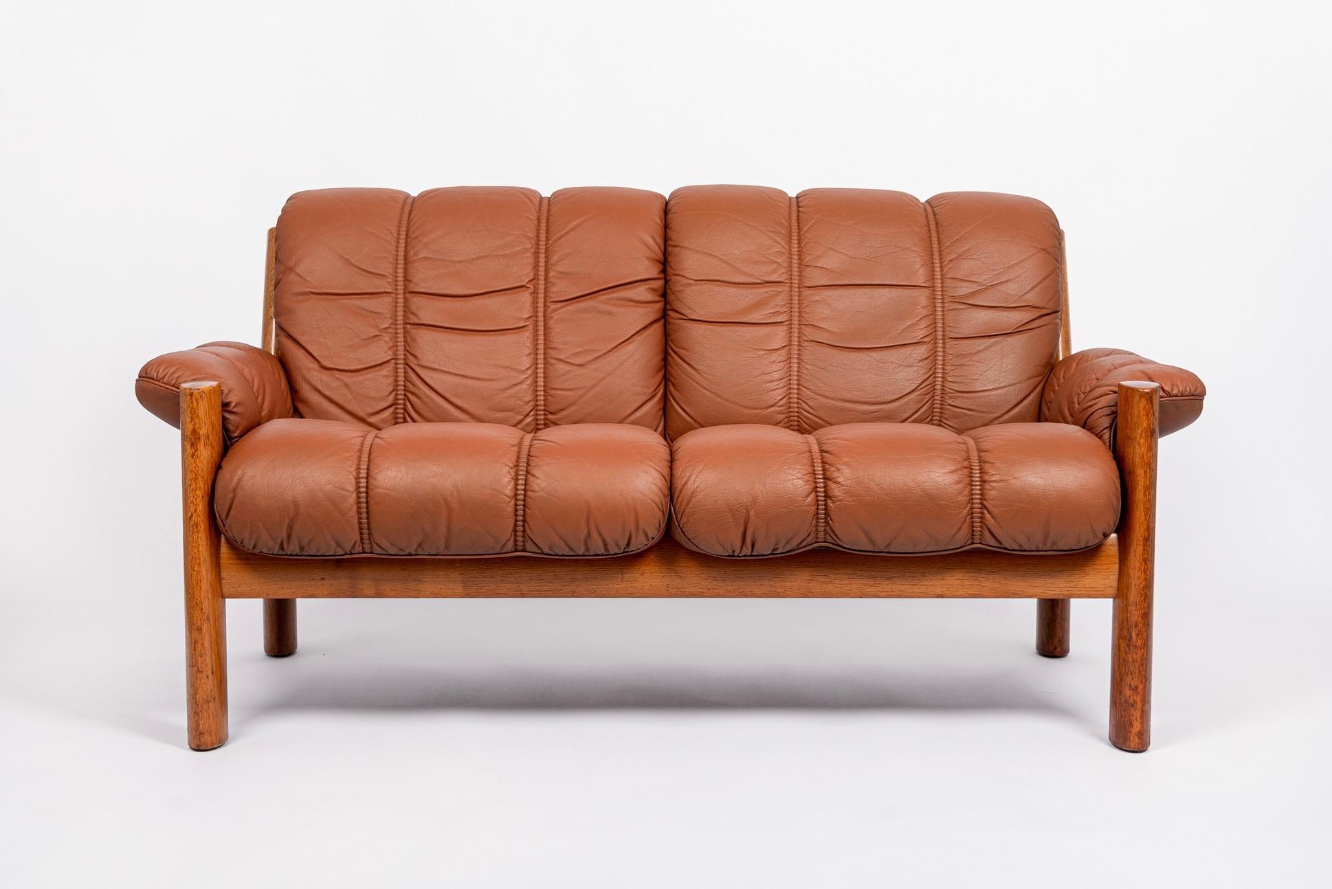 This vintage mid century modern Stressless Montana brown leather two-seat sofa was manufactured by Ekornes and made in Norway circa 1970. The sofa is designed for comfort and features a classic Scandinavian modern profile with clean, minimalist