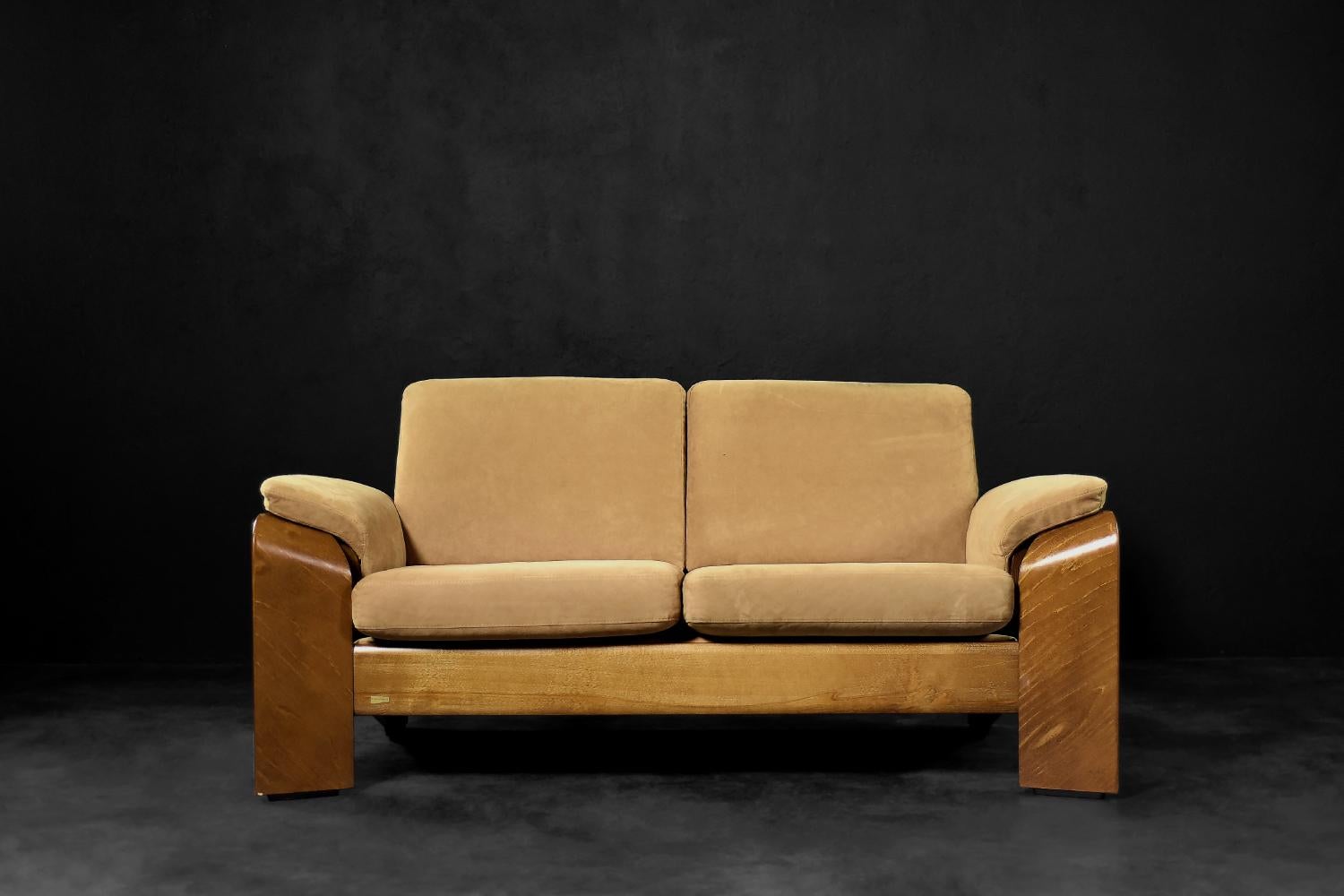 This modern two-seater sofa Pegasus Low Back Loveseat model, was manufactured by the Norwegian company Ekornes. The unconventional frame is made of bent teak wood in a warm shade of brown. Curved armrests flow smoothly into wide, rectangular legs.