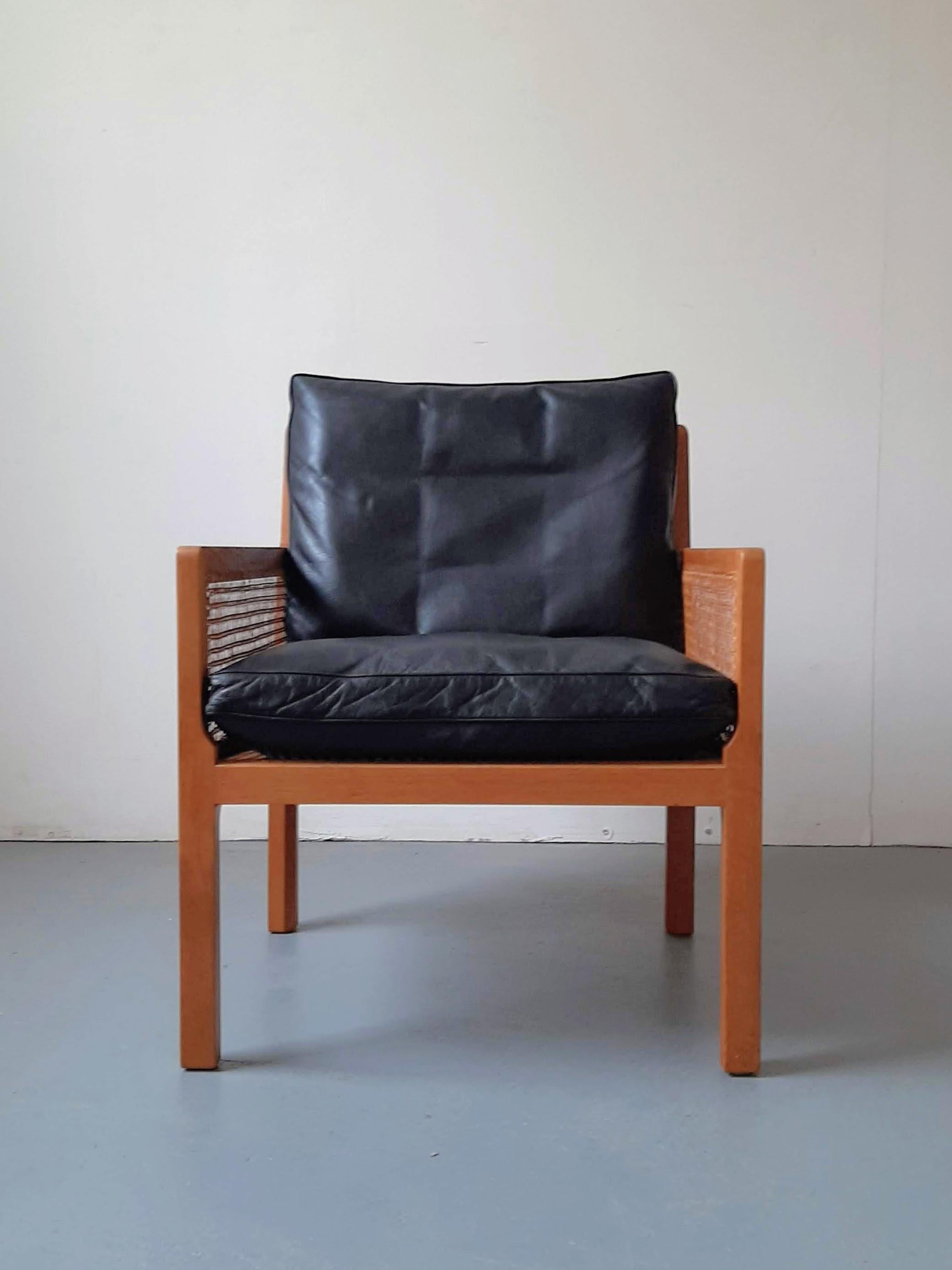 Beautiful oak framed lounge chair with cane sides, designed in 1964 by Bernt Petersen for Henrik Wørts Møbelsnedkeri. This stylish mid-century piece features down-filled cushions with black leather covers and is in great condition. The original cane