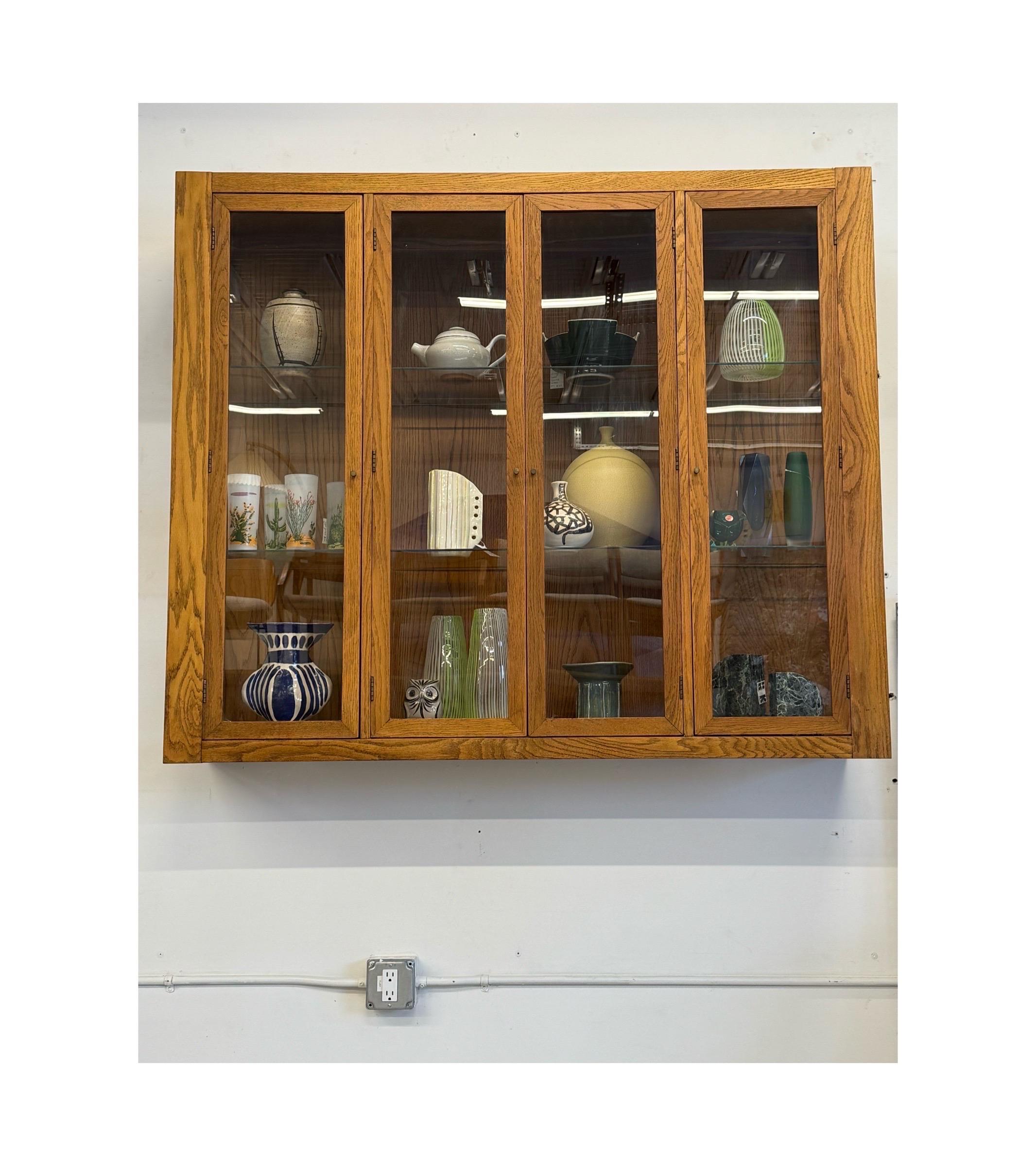 Armoire murale en chêne et verre du milieu du siècle. Parfait pour ceux qui ont une collection d'objets à exposer, il peut être monté à n'importe quelle hauteur. L'étui est fabriqué en bois de chêne au grain riche et vibrant. Quatre portes vitrées