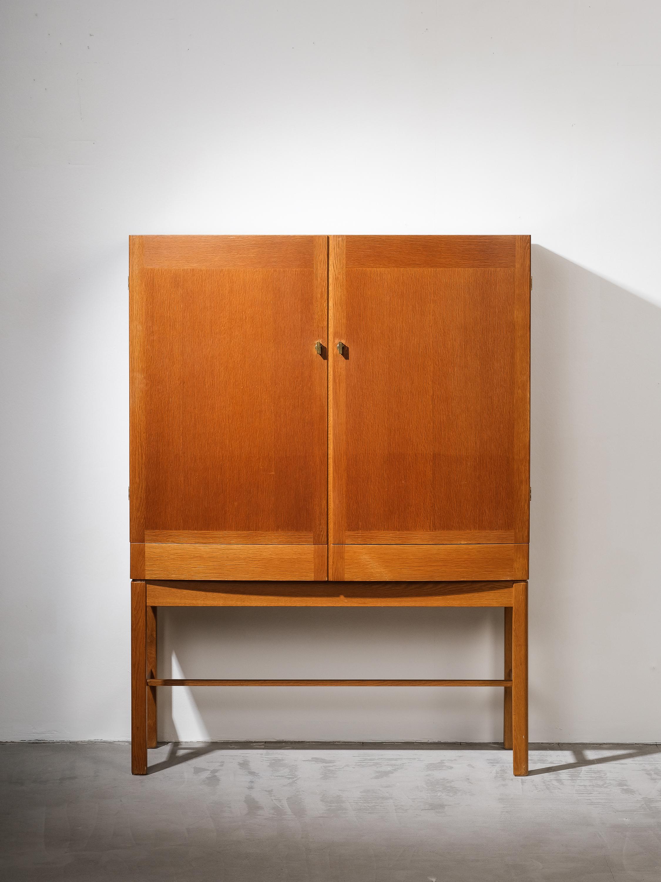 A cabinet in oak Gunnar Myrstrand for Källemo. Made in the 1960s in Sweden.

The double doors are slightly bent. Behind there are shelves and inner drawers. Brass door pulls.

Overall in a good condition, nicely patinated oak wood with honey patina.