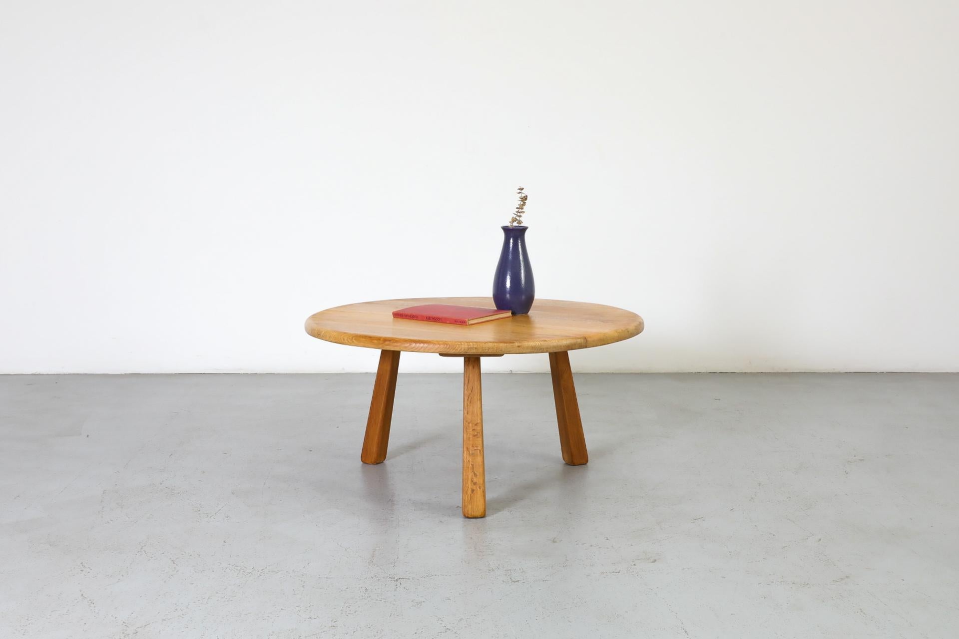 Table basse ou d'appoint ronde en chêne massif, inspirée par Charlotte Perriand, avec base tripode et pieds évasés. Il s'agit probablement d'un des premiers modèles produits par Meubelfabriek Osterwijk, connu pour ses meubles en chêne de style