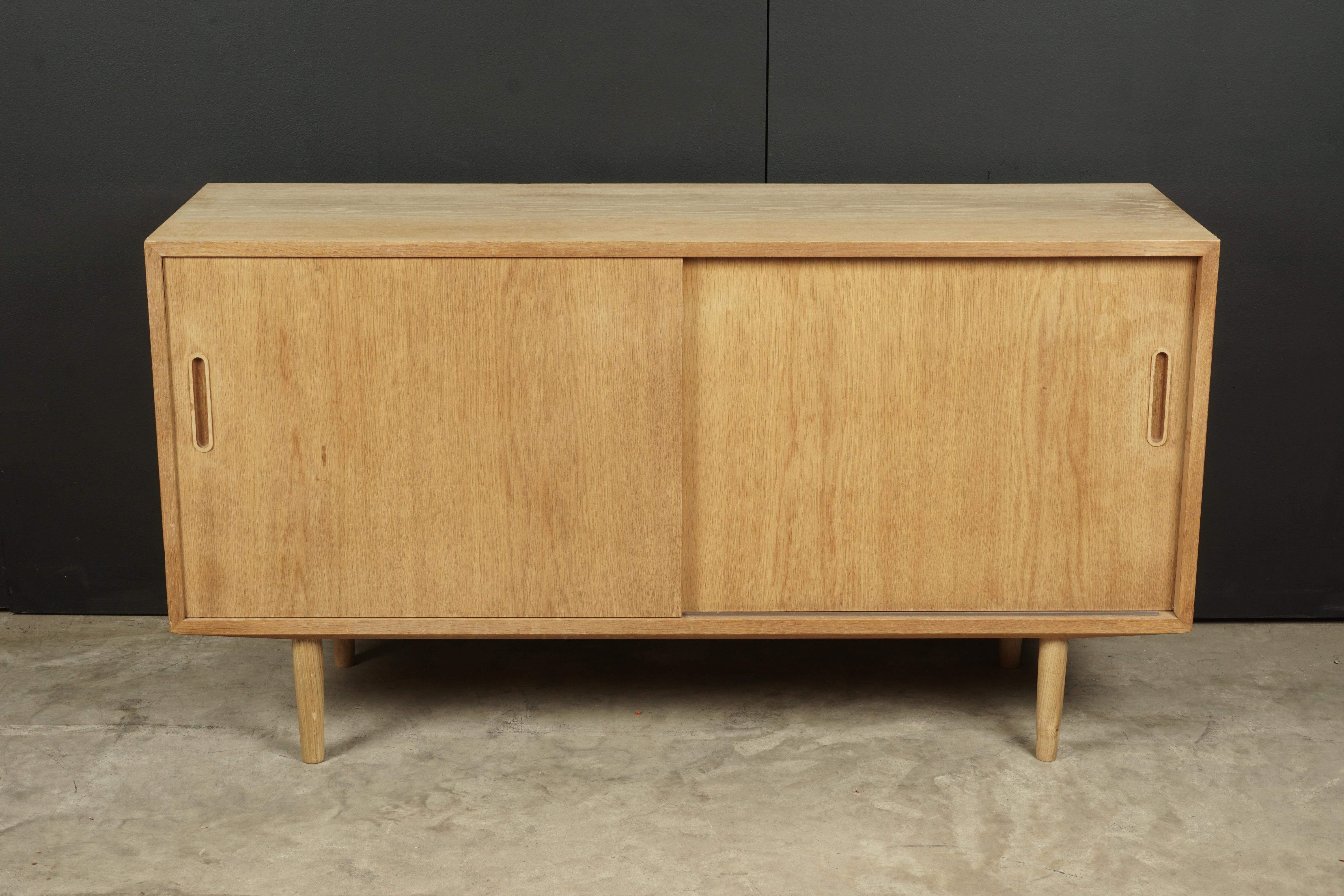 Midcentury oak credenza from Denmark, circa 1960. Two sliding doors with drawers and adjustable shelves. Danish control stamp on the reverse.