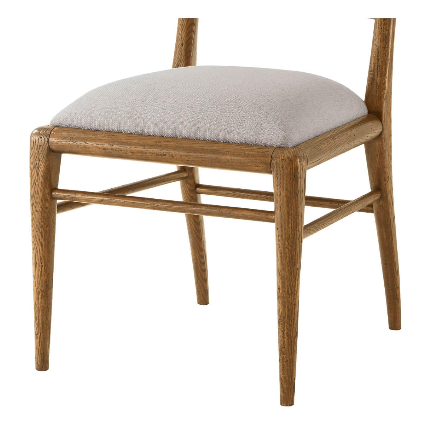 Chaise de salle à manger en chêne clair de style milieu de siècle dans notre finition dawn, avec un dossier et une assise rembourrés en tissu de lin performance qui ajoute confort et sophistication à ce design intemporel. Il repose sur des pieds