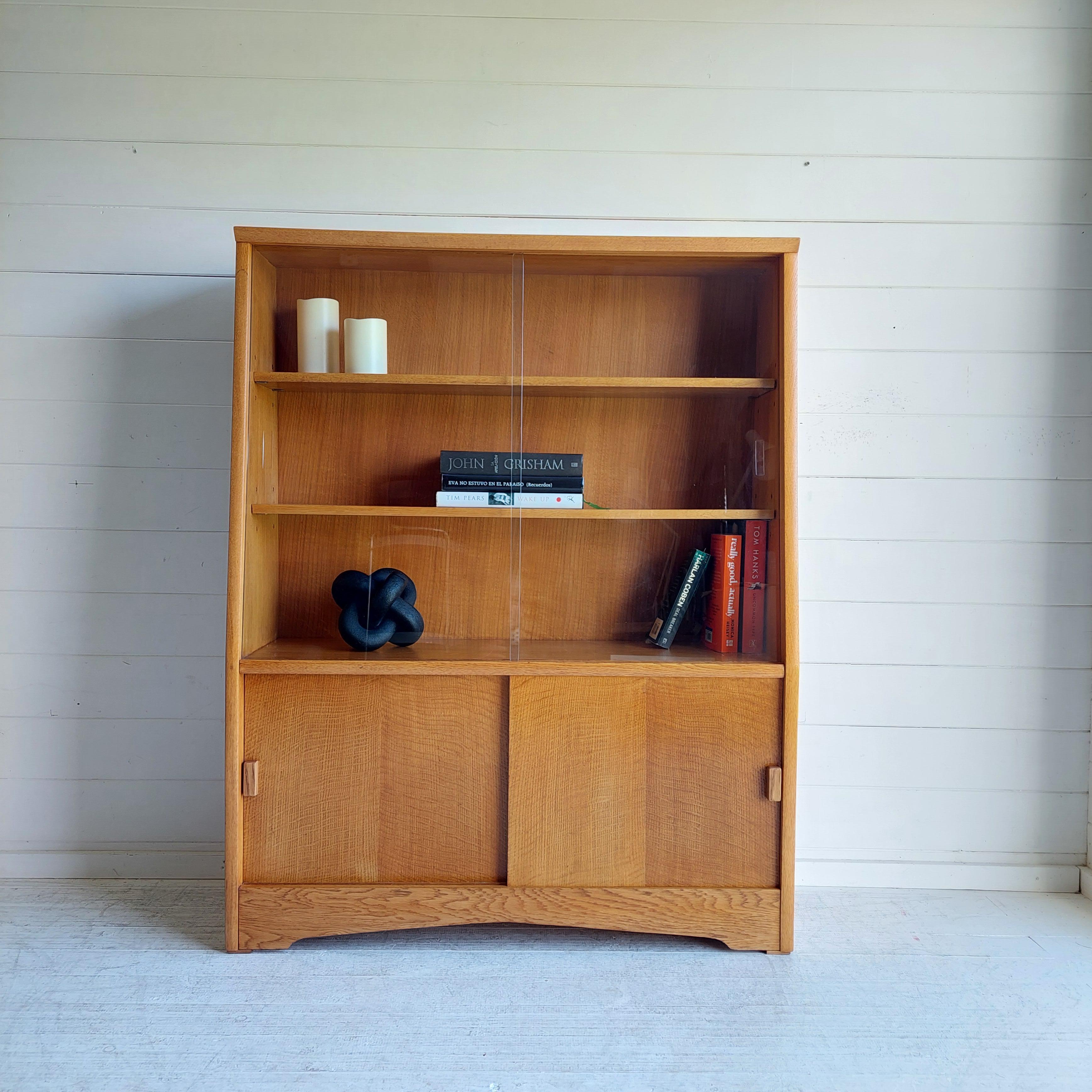 Beautiful Mid Century Oak Bookcase manufactured by Herbert E Gibbs
A wonderful 50s/60s  bookcase or display unit with sliding glass doors, shelves and cupboard section.
This is a top quality, sleek and stylish piece of furniture perfect for the