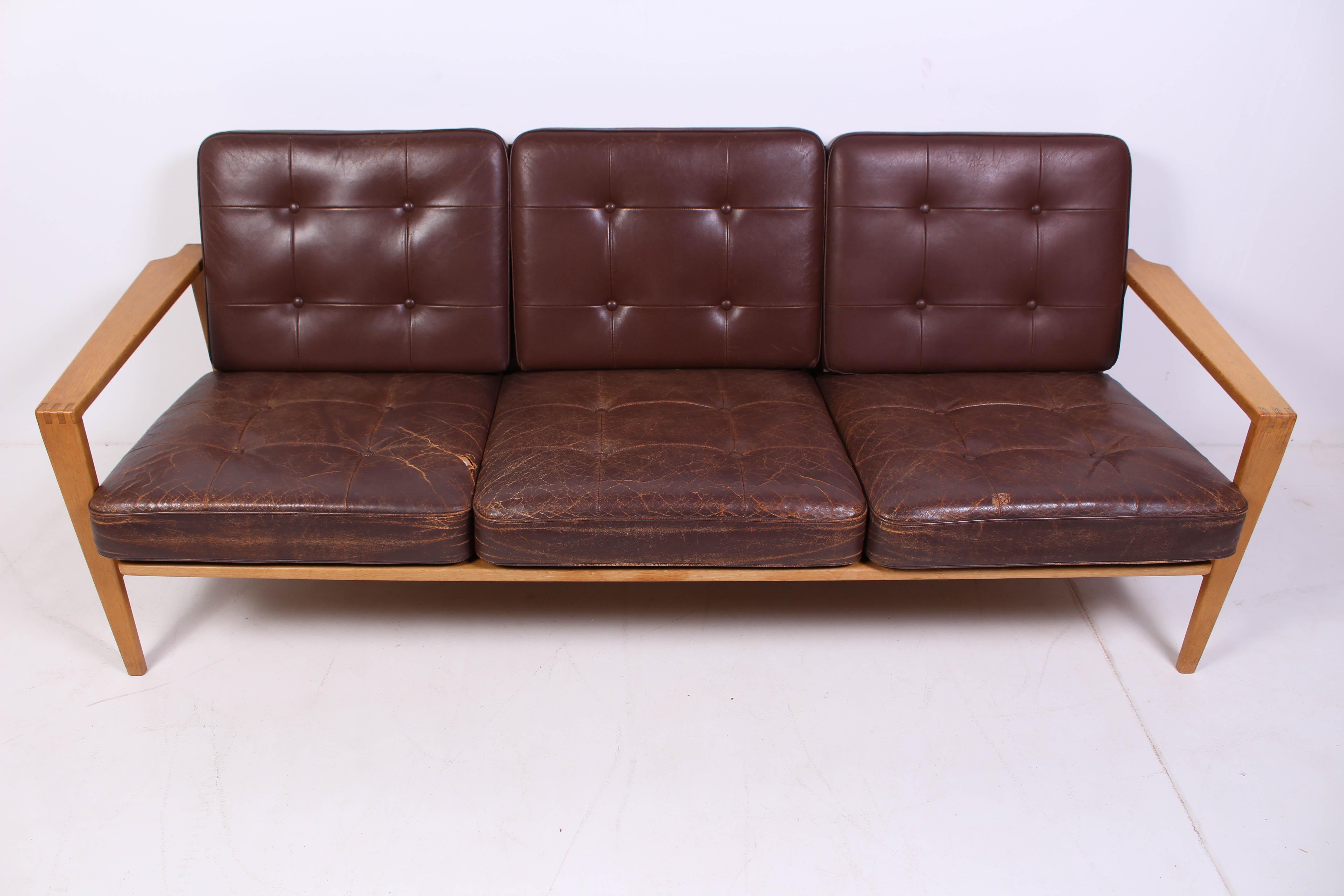 Oak and brown leather sofa by Danish designer Erik Wørtz. The model is called Kastrup. The oak frame and the back cushions are in good vintage conditions but the seat cushions have heavy signs of usage and tares and could be in need of upholstery.