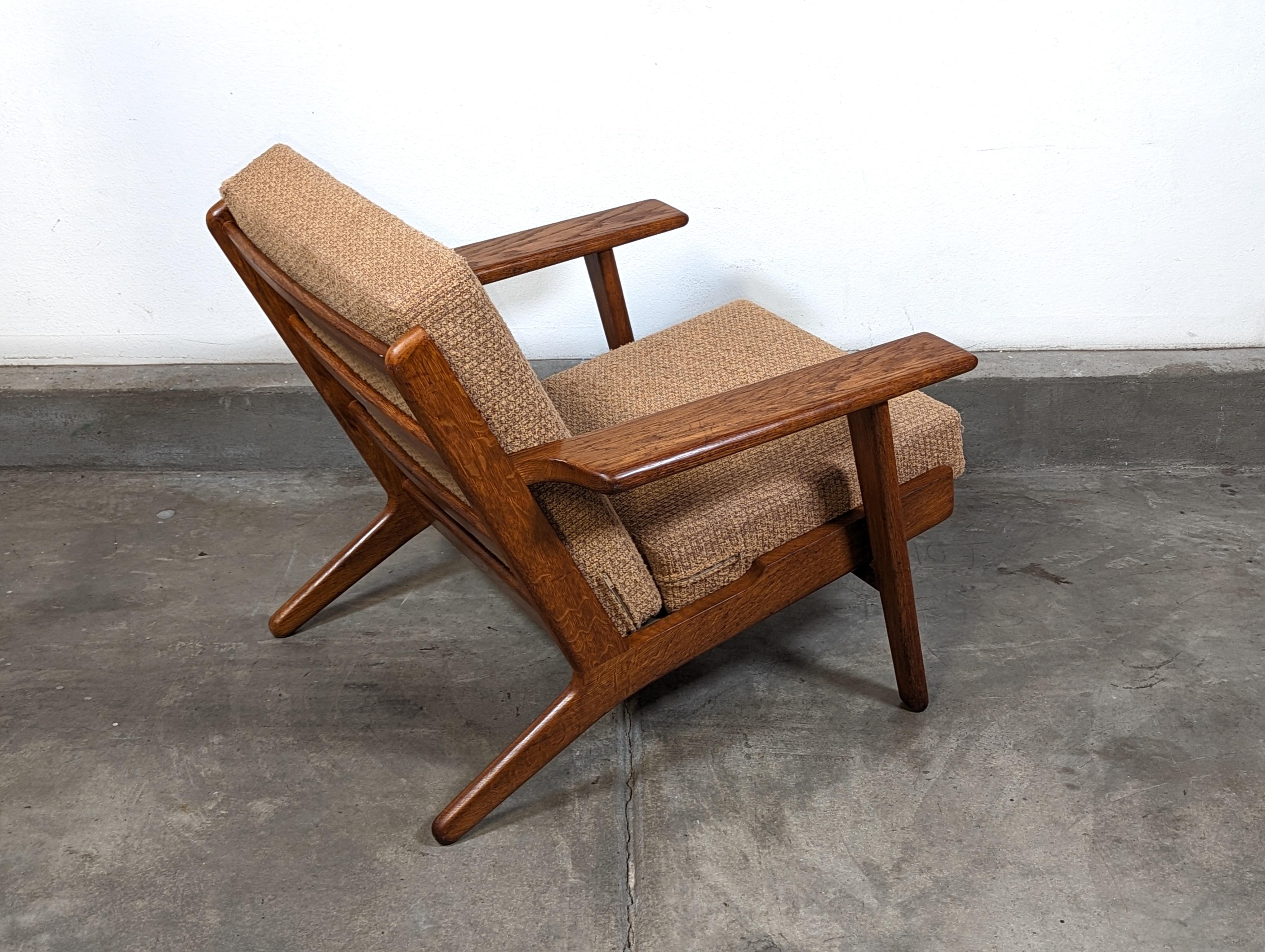 Versetzen Sie sich zurück in die Zeit des dänischen Designs mit diesem authentischen Loungesessel aus der Mitte des Jahrhunderts, der von dem legendären Hans Wegner entworfen und von der angesehenen Firma GETAMA hergestellt wurde. Dieses zeitlose