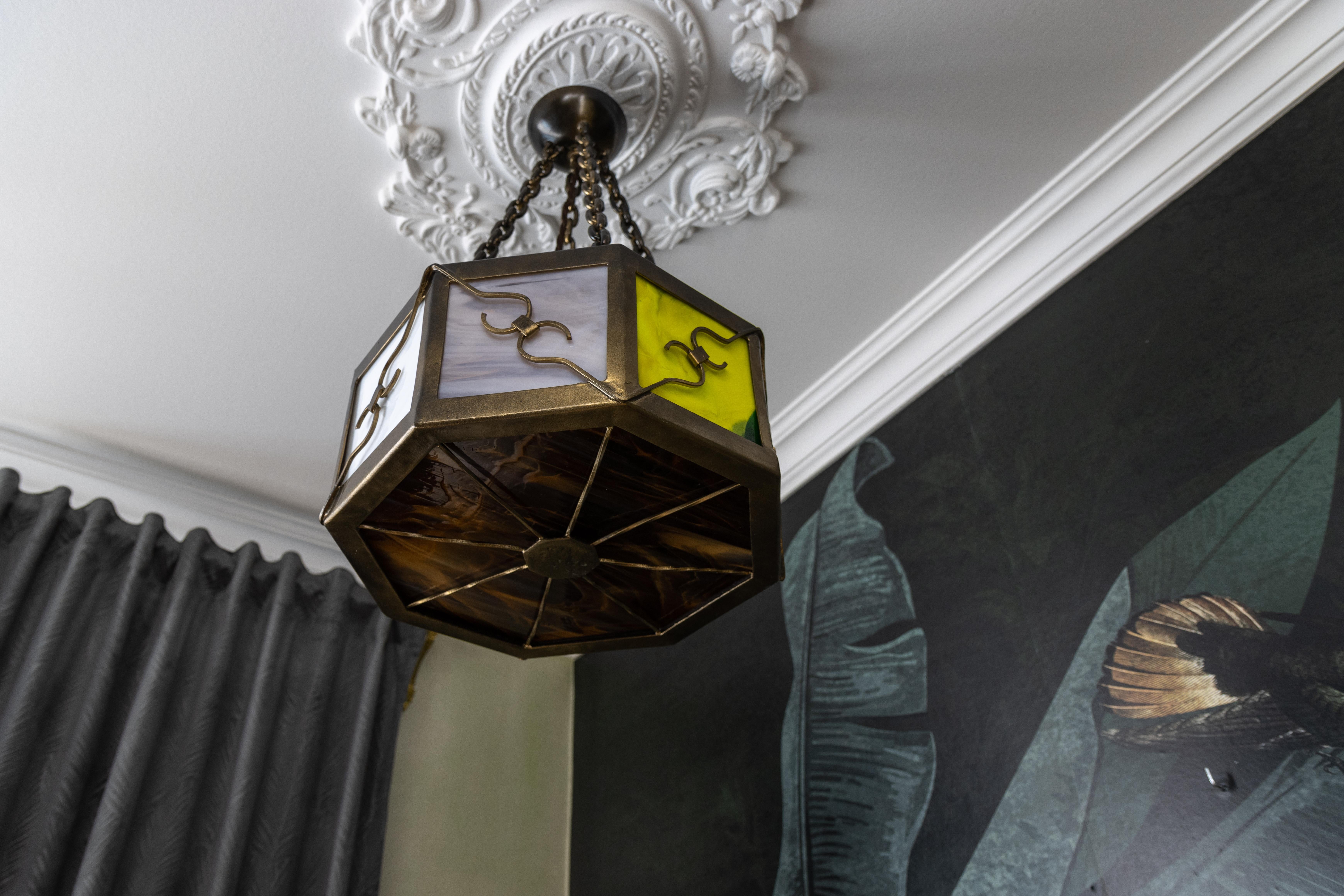 Midcentury octagonal metal and polychrome Tiffany glass pendant light, Germany, 1950s.

This striking mid-century pendant light, crafted in Germany in the 1950s, features an elegant octagonal form with a combination of patinated metal and