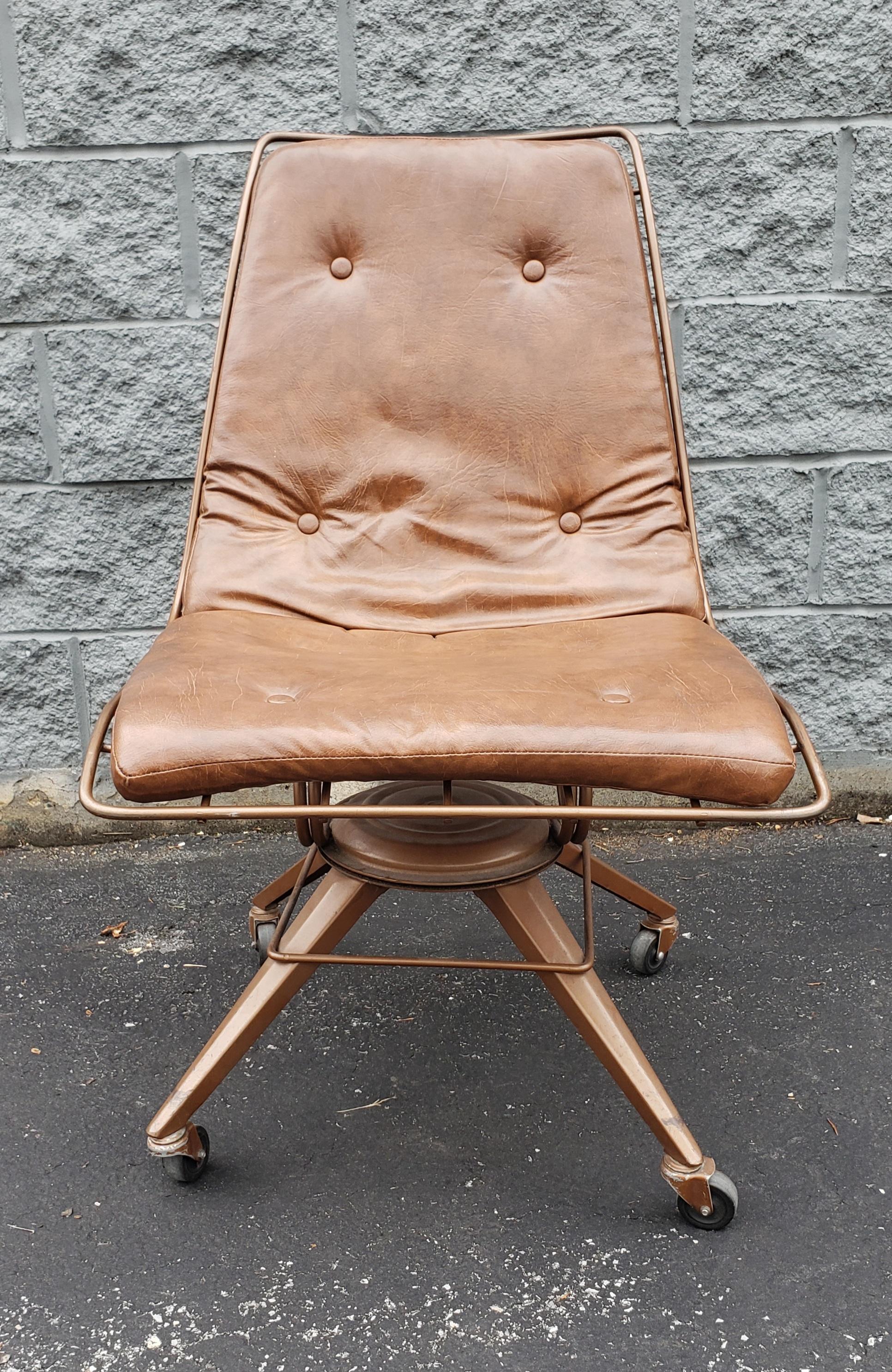 A rare midcentury metal swiveling office chair on wheels with PU leather seat and back cushion. Very good vintage condition.
Chair measures 21