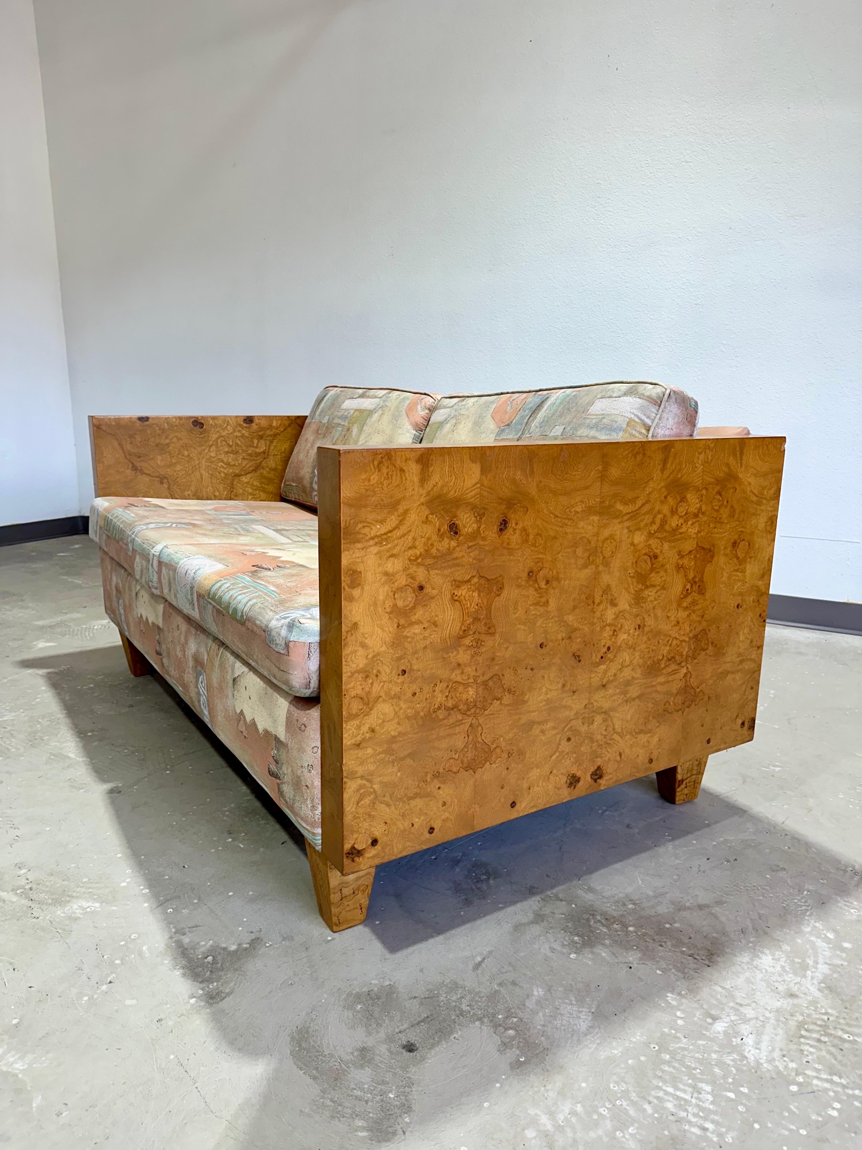 Mid Century Modern Milo Baughman Style Olive Burl Wood Cased two seater Loveseat. Impressive grain patterns on both sides, professionally reupholstered in the early 1990’s in pastel abstract print fabric. Original tags are no longer present.