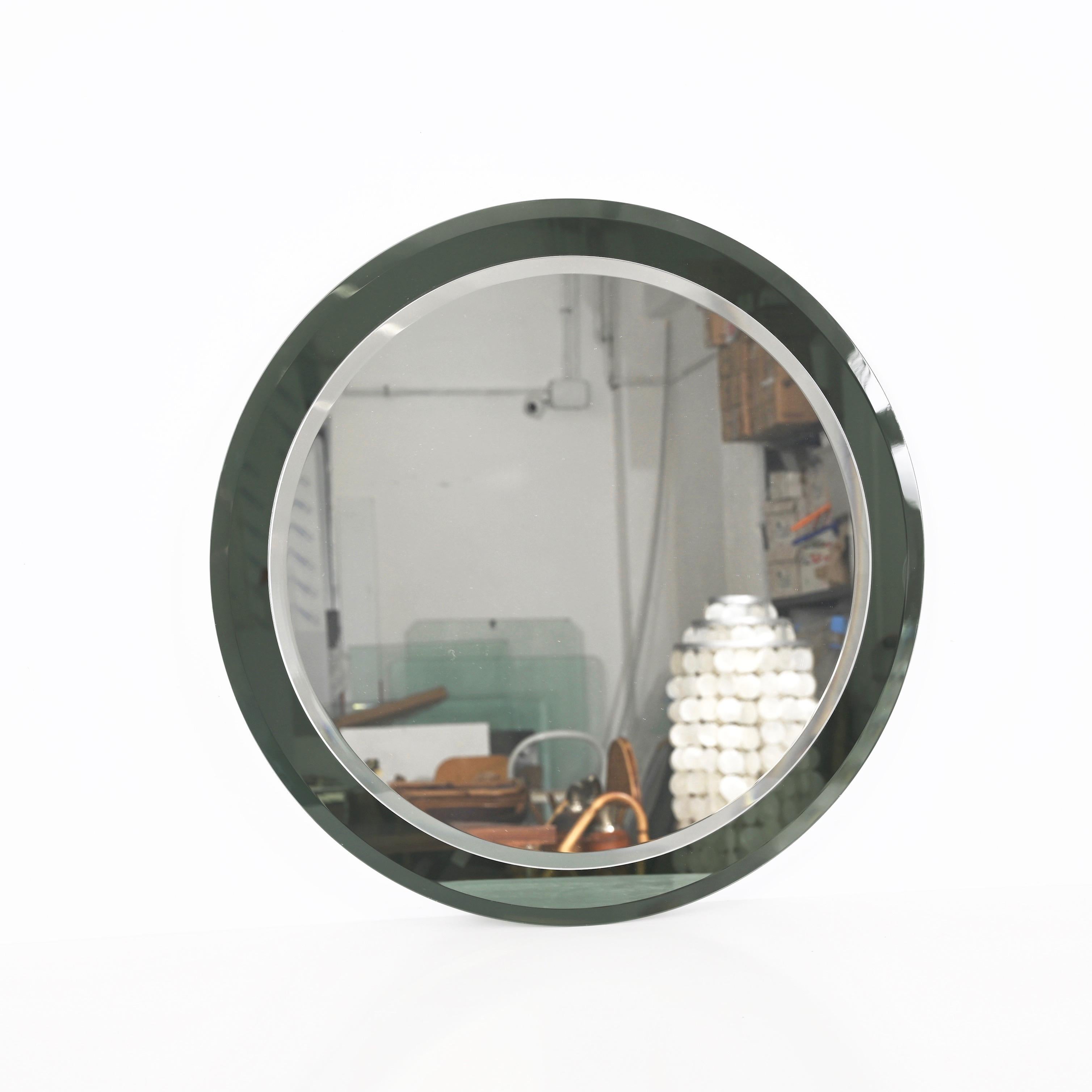 Striking mid-century double bevelled round mirror. This fantastic object was produced in Italy in the 70s by Metalvetro.

The mirror features an extraordinary mirrored glass frame in an olive green color that fades to a light grey depending on the